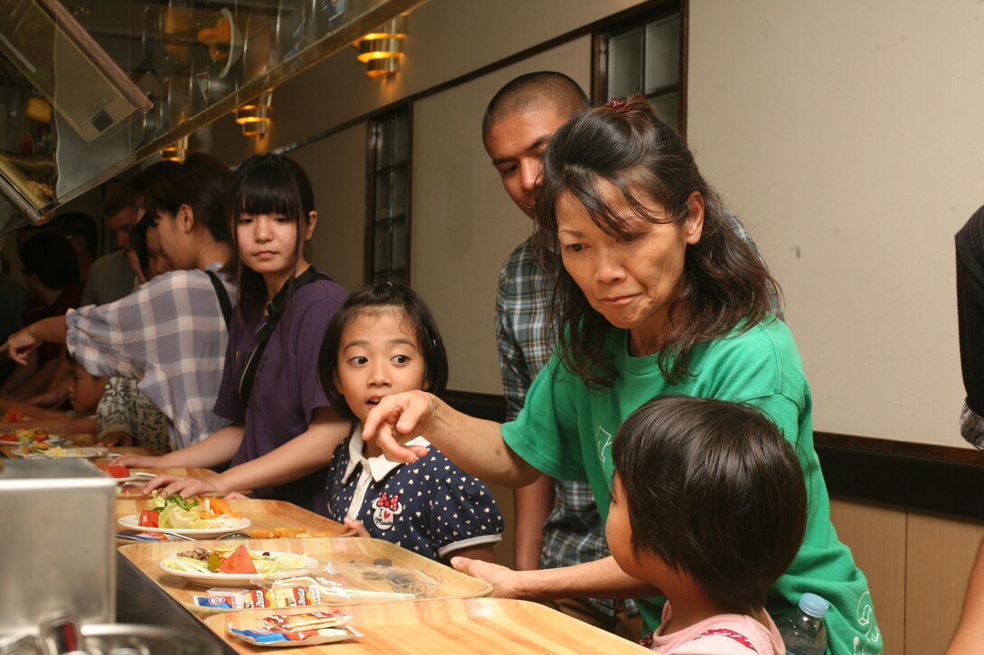 Caretakers and children from the Nagomi Nursing Home for Children choose food from the salad bar of the Camp Kinser mess hall during a tour of the camp Aug. 3. During the tour, the group visited a storage warehouse, the mess hall, the Battle of Okinawa historical display and the bowling alley. The tour provided an opportunity for the children to experience a different culture and to develop relationships with Marines and sailors. The tour was led by Marines and sailors with 3rd Supply Battalion, Combat Logistics Regiment 35, 3rd Marine Logistics Group, III Marine Expeditionary Force. 