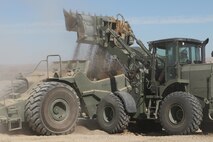 Heavy equipment operators from Marine Wing Support Squadron 272 load up a scraper full of sand and rocks by the flight line at Camp Wilson aboard Marine Corps Air-Ground Combat Center Twentynine Palms, Calif., July 31. The material will later be evenly dispersed along the flight line and used as an erosion preventative.