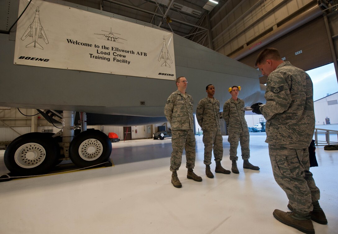 Staff Sgt. Ryan Wooley, 28th Aircraft Maintenance Squadron weapons load crew team chief, briefs and directs his team as they prepare for real-world scenarios in the Load Crew Training Facility at Ellsworth Air Force Base, S.D., Aug. 13, 2013. Woolie is responsible for overview and guidance to ensure that his team is proficient and capable of arming Ellsworth’s B-1 bomber fleet. (U.S. Air Force photo by Airman 1st Class Zachary Hada/Released)