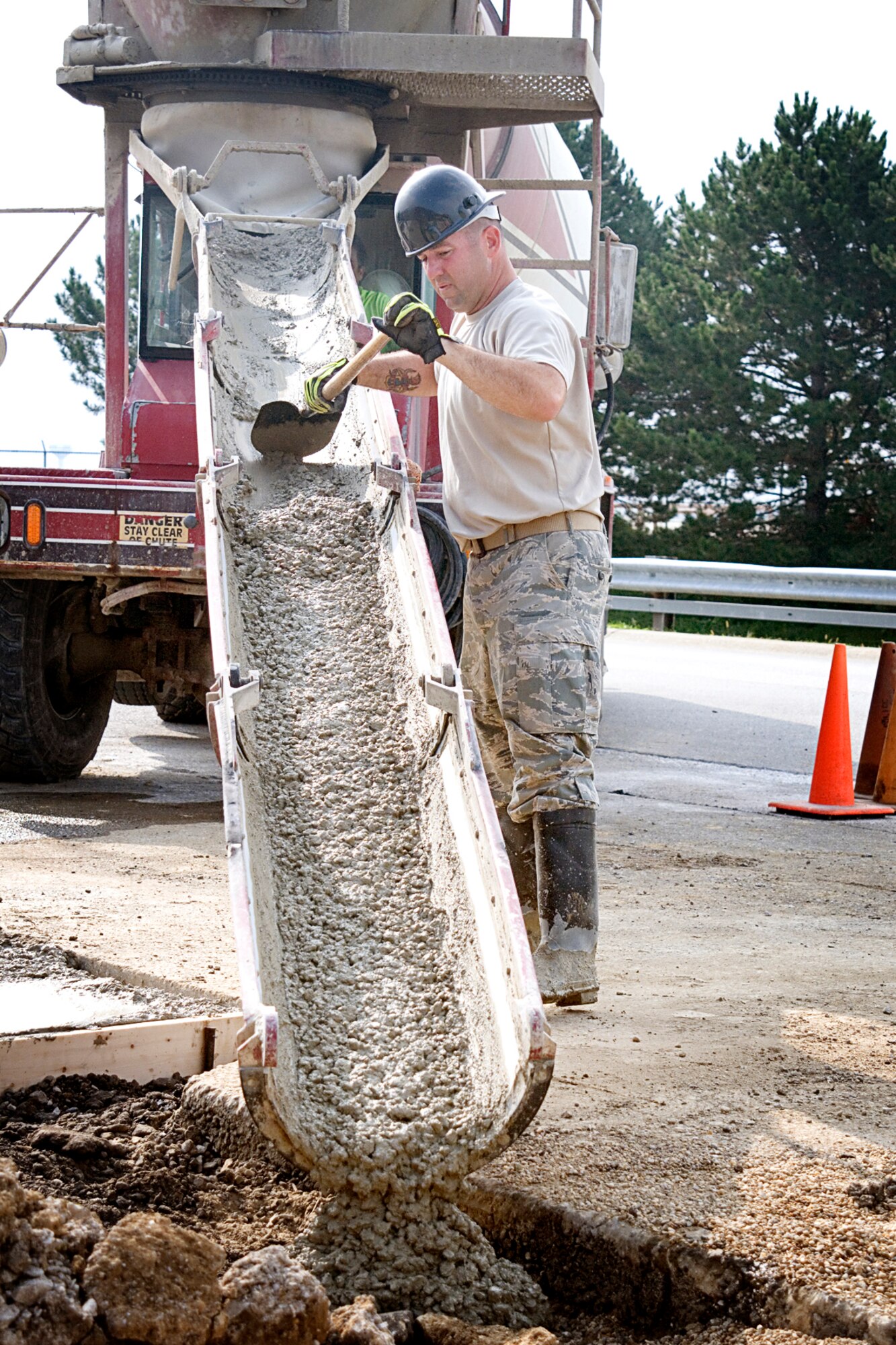 Senior Master Sgt. Nate Colborn, 434th Civil Engineer Squadron structural superintendent, scrapes cement as it flows down the trough into a form created to expand the patio at Bldg. 595. Colborn and other "Dirt Boys" from the 434th CES expanded the patio between the 434th Maintenance Group and base exchange entrances as part of a training opportunity at Grissom Air Reserve Base on Aug. 8, 2013. (U.S. Air Force photo/Tech. Sgt. Doug Hays)