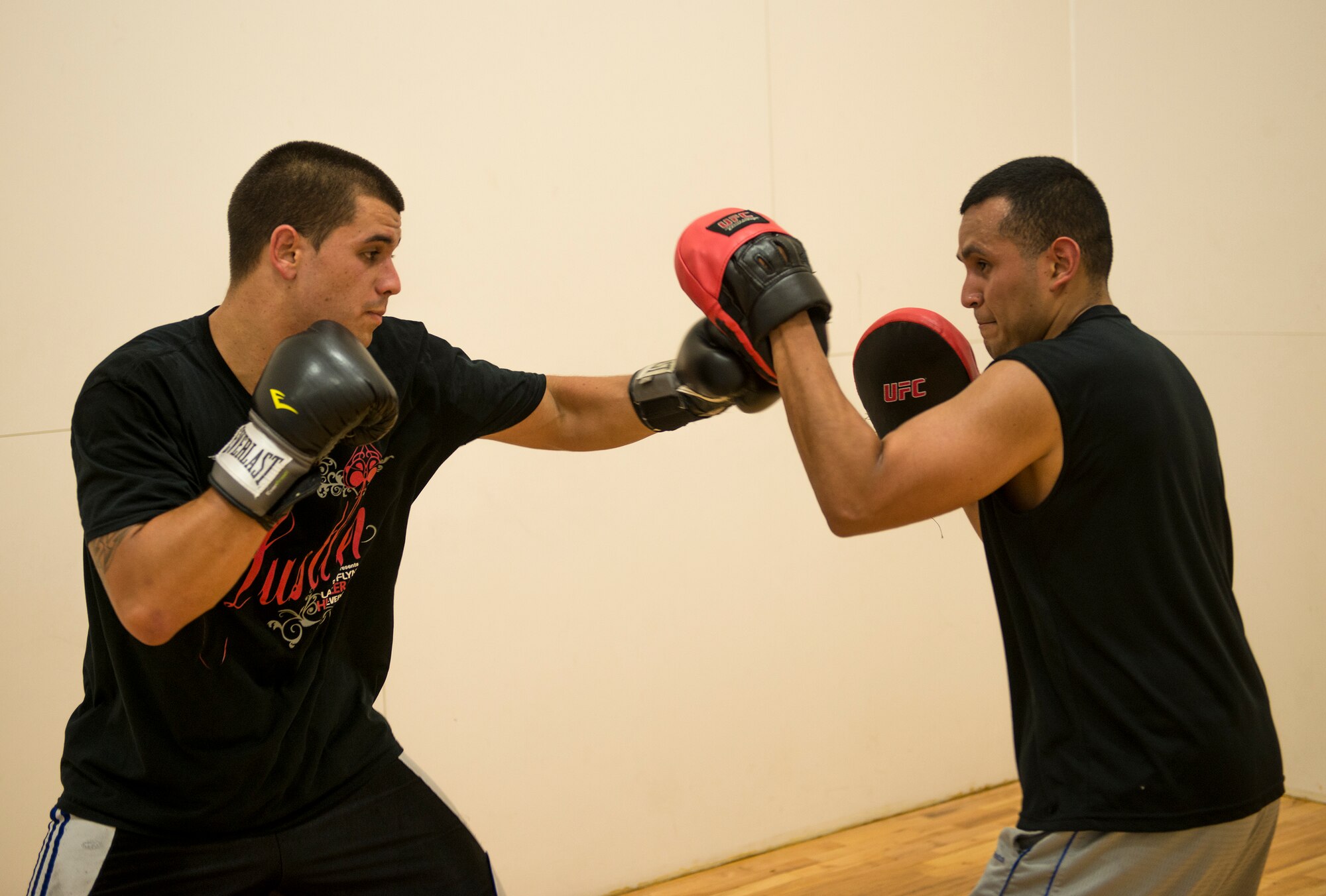 U.S. Air Force Staff Sgt. Edgar Sotelo, 75th Aircraft Maintenance Unit crewchief, calls out combinations as Airman 1st Class Conor Fergus, 75th Aircraft Maintenance Unit aircraft armament journeyman, strikes focus mitts in the Freedom I Fitness Center at Moody Air Force Base, Ga., June 26, 2013. Boxing can help eliminate everyday pressures that may negatively impact your thought process. (U.S. Air Force photo by Senior Airman Douglas Ellis/Released)
