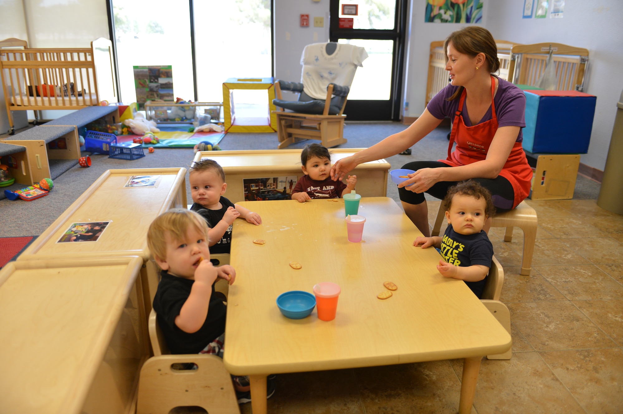 Henrieta Western, 56th Force Support Squadron Child Development Center program assistant, assists children with a mid-day snack at the CDC at Luke Air Force Base. The CDC’s activity centers include reading, play, music, painting, water play and sand tables. For more information, call 623-856-6338. (U.S. Air Force photo/Airman 1st Class Devante Williams)