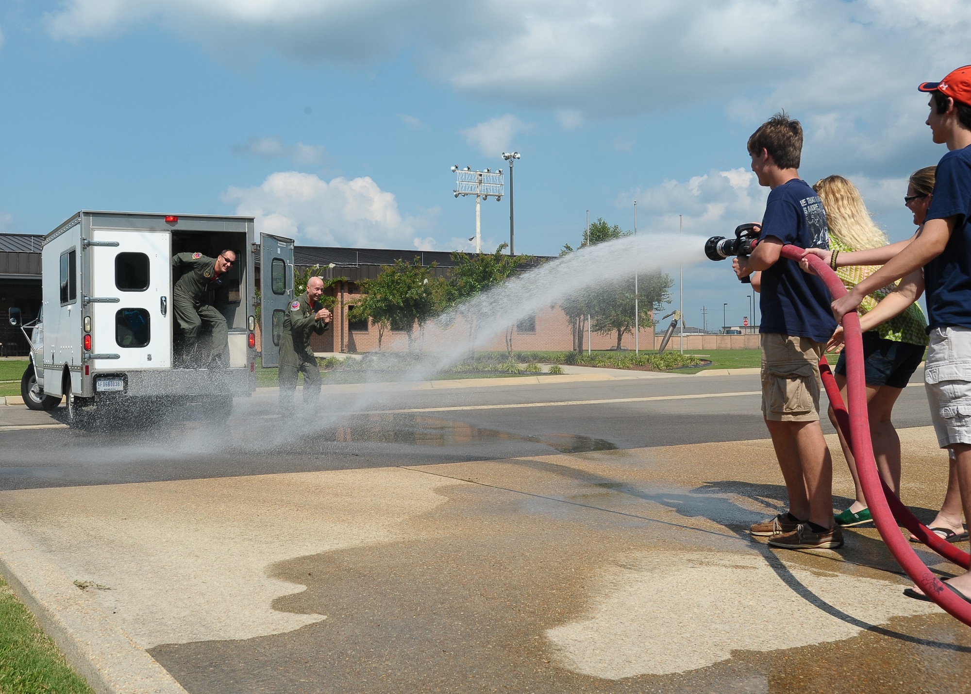 Family members of Lt. Col. Michael Kendrick and Lt. Col. Barry Tye, both from the 43rd Flying Training Squadron, spray down the retirees as the exit from the transportation van from the flight line August 14. Kendrick and Tye served Columbus AIr Force Base for over 19 years and flew over 5,800 hours in a T-1A Jayhawk over the course of their Air Force careers.  (U.S. Air Force Photo/Airman 1st Class Stephanie Englar)