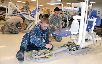 Petty Officer 2nd Class Brandon Richardson (left) and Pfc. Miguel Labra inspect the air supply on a dental treatment unit in the Dental and Sterilizer Equipment course. This is one of 12 courses service members must complete during Biomedical Equipment Maintenance Technician training at the Medical Education and Training Campus on Joint Base San Antonio-Fort Sam Houston. (Photo by Lori Newman, JBSA-Fort Sam Houston Public Affairs)