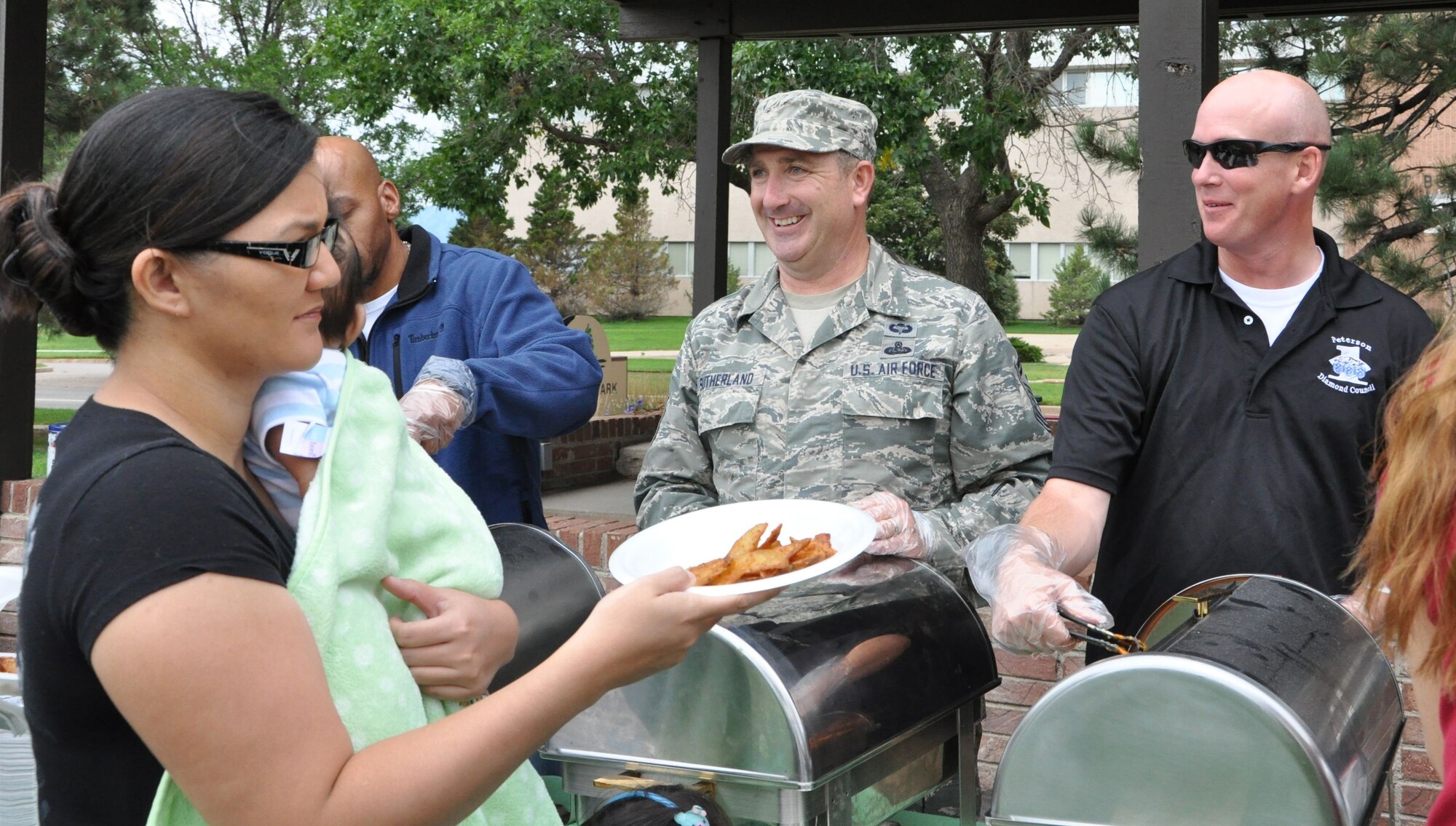 PETERSON AIR FORCE BASE, Colo. – Senior Master Sgt. Tim Sutherland and Master Sgt. Joseph Beymer, both members of the Team Pete First Sergeants Council, serve chicken wings during the Family Festival and Deployed Families Dinner Aug. 9 at Patriot Park. The dinner and festival included free food, music and carnival activities for all members of Team Pete. (U.S. Air Force photo/1st Lt. Stacy Glaus)