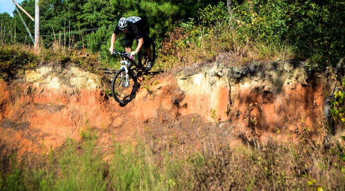 Tech. Sgt. Nathan Swab, 628th Communications Squadron quality assurance evaluator and a Low Country Fat Tire Freaks member, rolls down a ledge Aug. 13, 2013, at Marrington Plantation on Joint Base Charleston -Weapons Station, S.C. The Marrington trail system is more than 19 miles long and has an average of 6,000 visitors a year. The LCFTF is a group of volunteers who help maintain the trails. (U.S. Air Force photo/Senior Airman Jared Trimarchi) 
