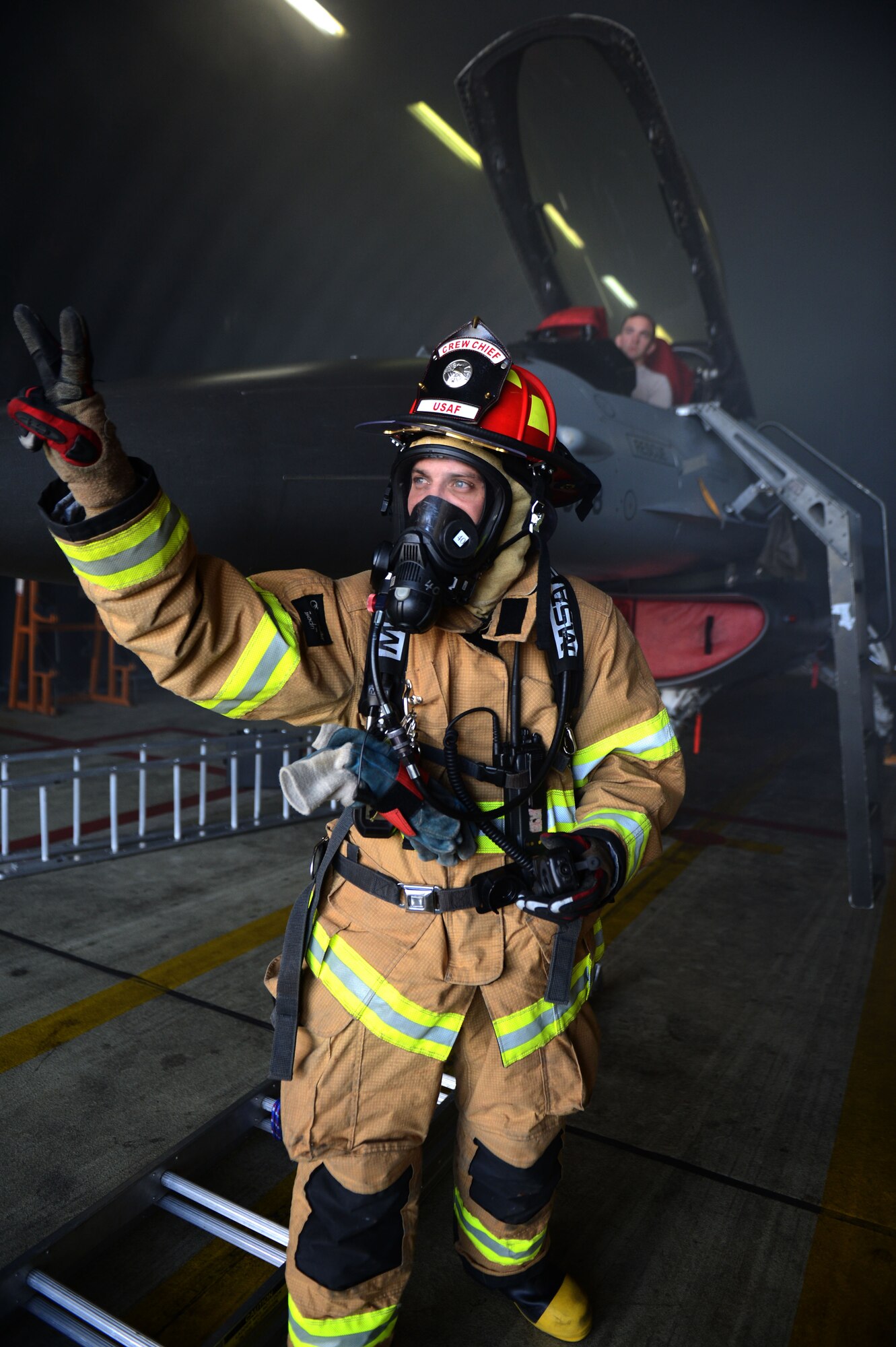 SPANGDAHLEM AIR BASE, Germany – U.S. Air Force Tech. Sgt. Michael Tellish, 52nd Civil Engineer Squadron crew chief from Pittsburg, communicates to his fellow firefighters with hand gestures during an aircraft fire training exercise Aug. 14, 2013. Communicating with an oxygen mask is difficult, but fire protection Airmen use any means necessary to relay a message during an incident such as this. (U.S. Air Force photo by Airman 1st Class Gustavo Castillo/Released)