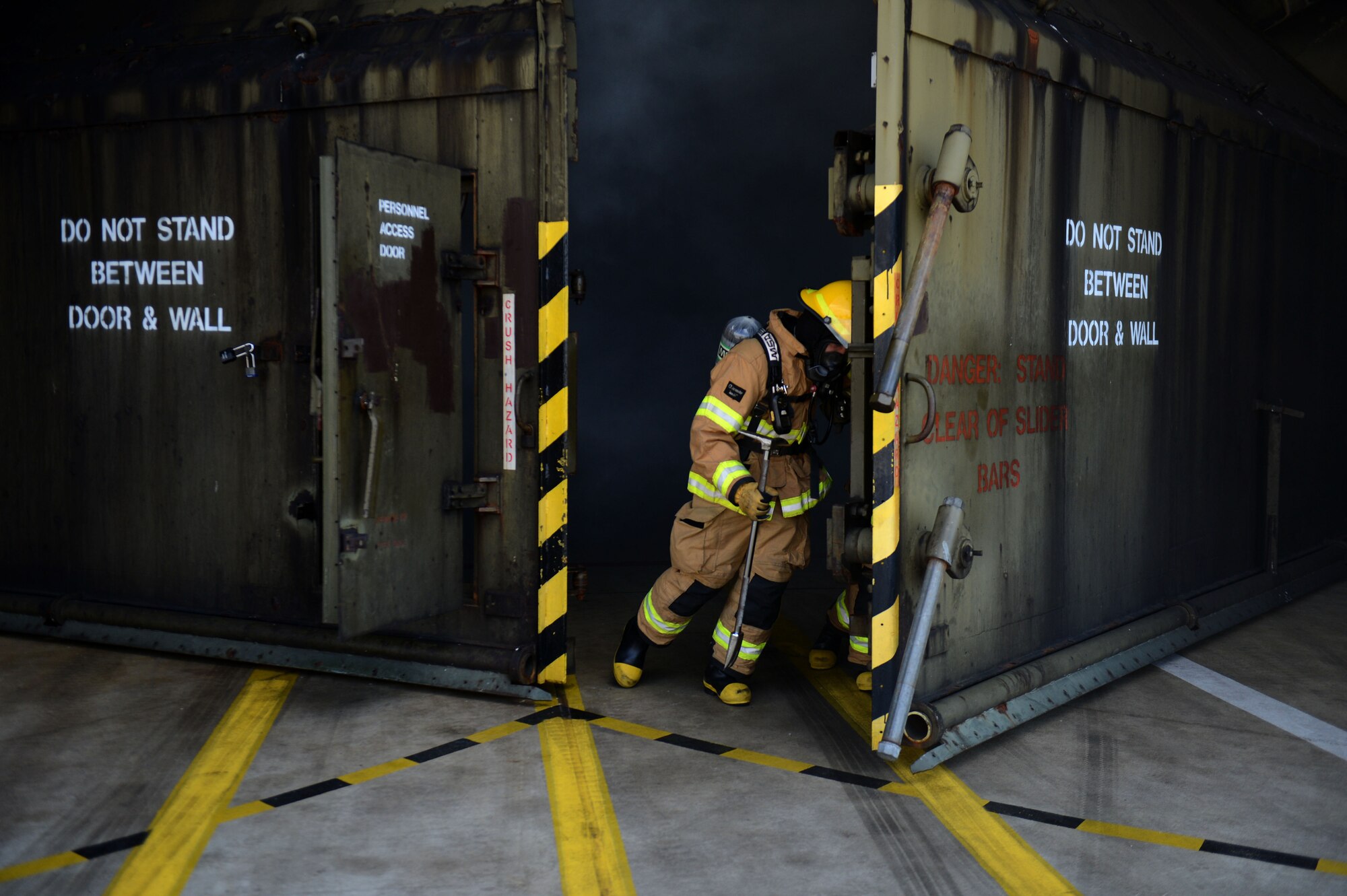 SPANGDAHLEM AIR BASE, Germany – U.S. Air Force Airman 1st Class Joshua McGath, 52nd Civil Engineer Squadron fire protection technician from Stewart, Fla., opens the doors of a hardened aircraft shelter during an aircraft fire training exercise Aug. 14, 2013. In addition to learning to feel doors for heat, firefighters must also understand the need to wait until a fire hose is positioned near the entrance of a structure prior to entry, ensuring  the safety of all rescuers. (U.S. Air Force photo by Airman 1st Class Gustavo Castillo/Released) 