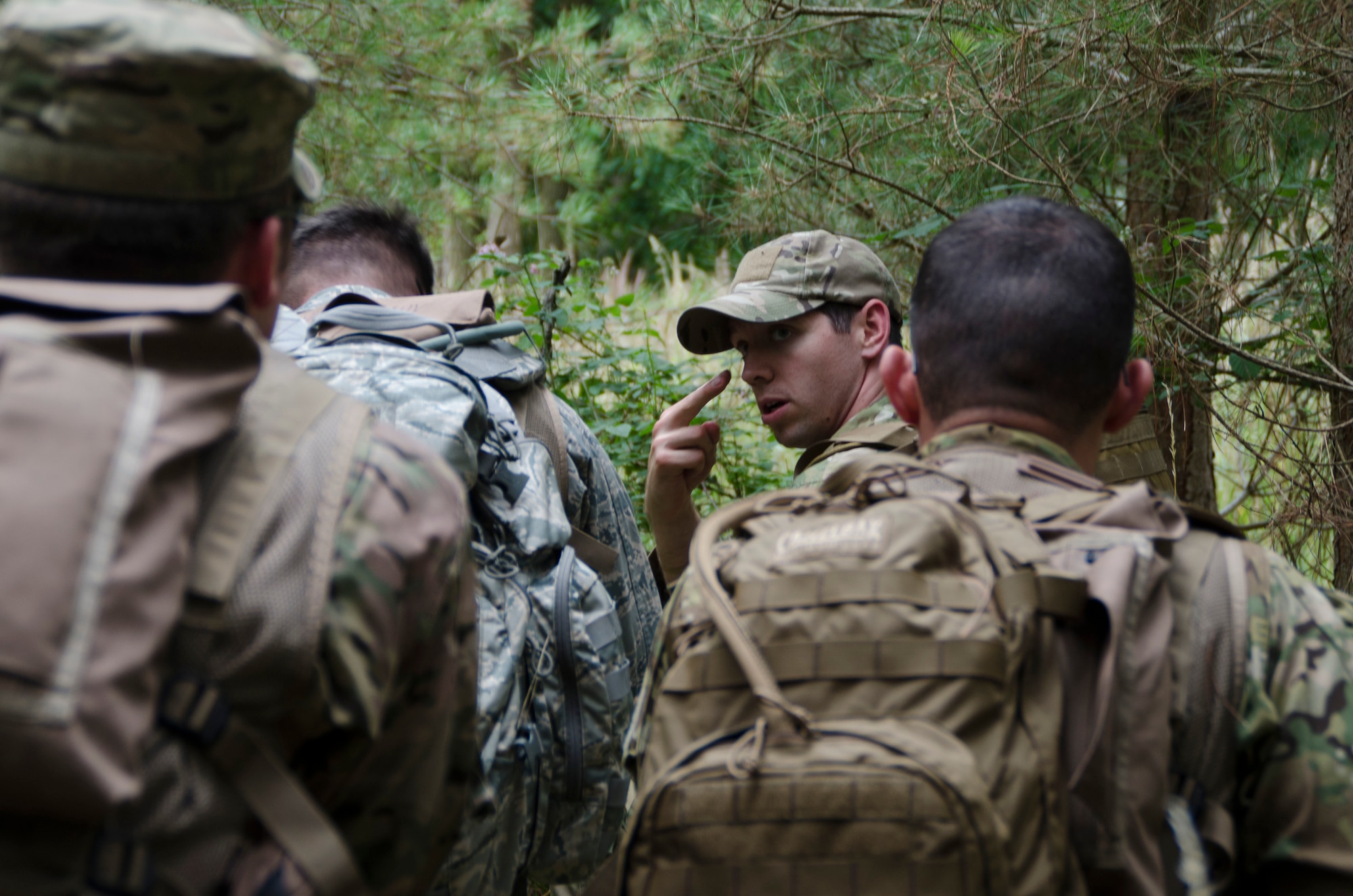 Staff Sgt. Jacob Schmidt, 352nd Special Operations Support Squadron Survival, Evasion, Resistance and Escape specialist, signals to airmen from the 352nd Special Operations Group to be on the lookout during combat survival training at Stanford Training Area, England, Aug. 6, 2013. The training covered other aspects of combat survival such as land navigation and evasion tactics. (U.S. Air Force photo by Staff Sgt. Stephen Linch)