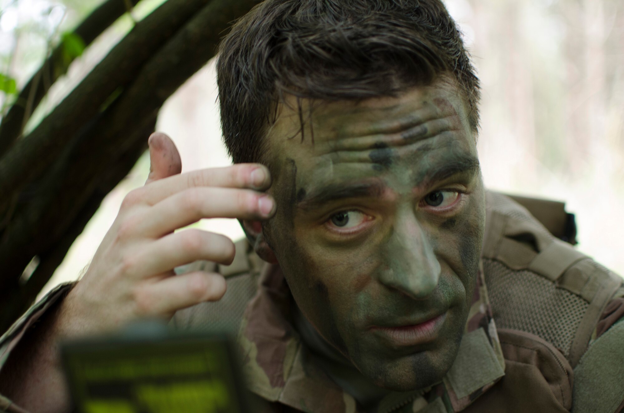 Capt. Branden Witt, 7th Special Operations Squadron CV-22 Osprey pilot, puts on camouflage during combat survival training at Stanford Training Area, England, Aug. 6, 2013. The training covered other aspects of combat survival such as land navigation and evasion tactics. (U.S. Air Force photo by Staff Sgt. Stephen Linch)