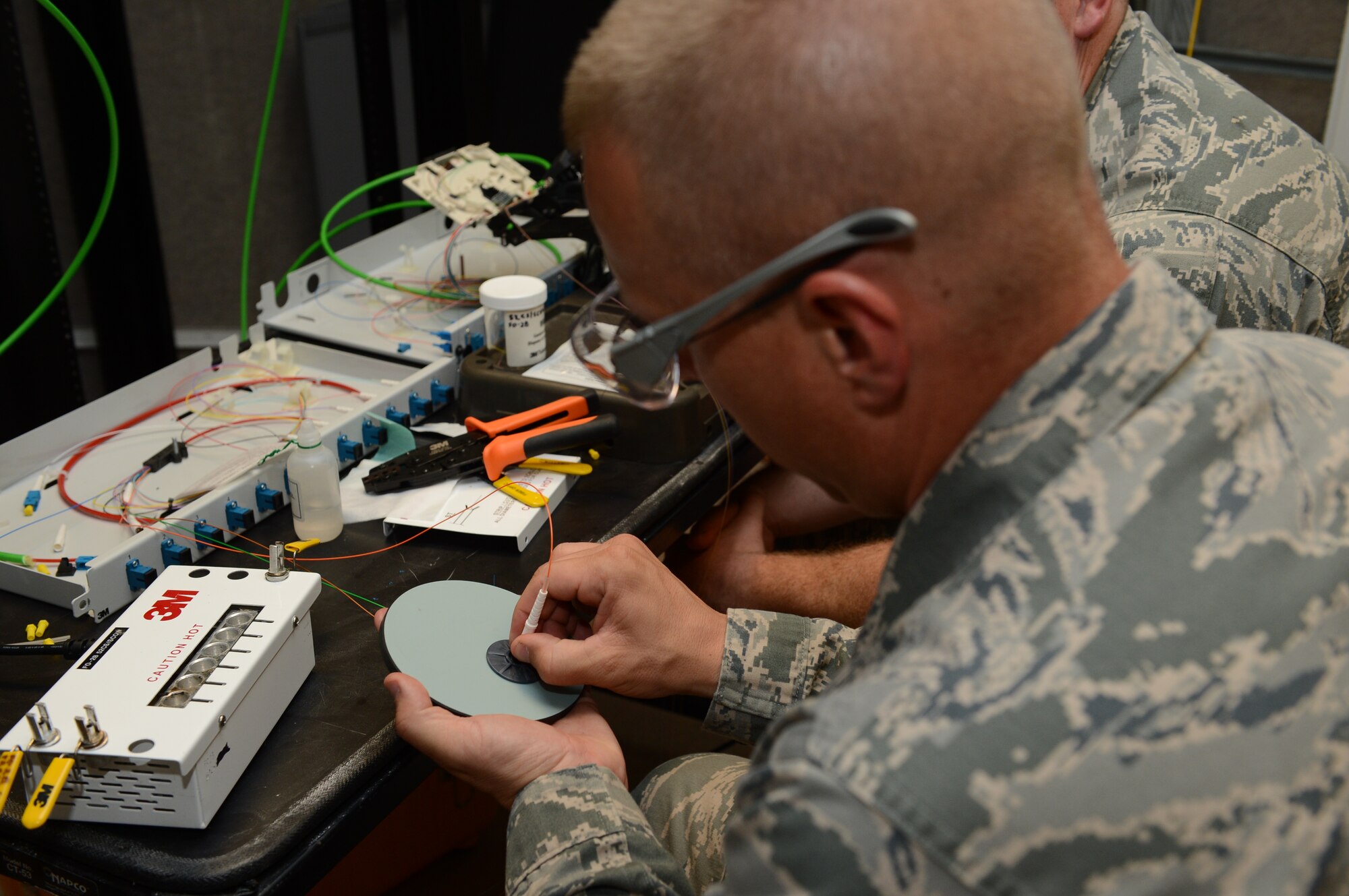 SPANGDAHLEM AIR BASE, Germany – U.S. Air Force Chief Master Sgt. Matthew Grengs, 52nd Fighter Wing command chief master sergeant, polishes the end of a fiber optic cable with fine sandpaper Aug. 14, 2013. Polishing the fiber is necessary to remove excess epoxy. Fiber optic cables are used for mass data transfers that support more than 60 terabits of data per strand. (U.S. Air Force photo by Airman 1st Class Kyle Gese/Released)
