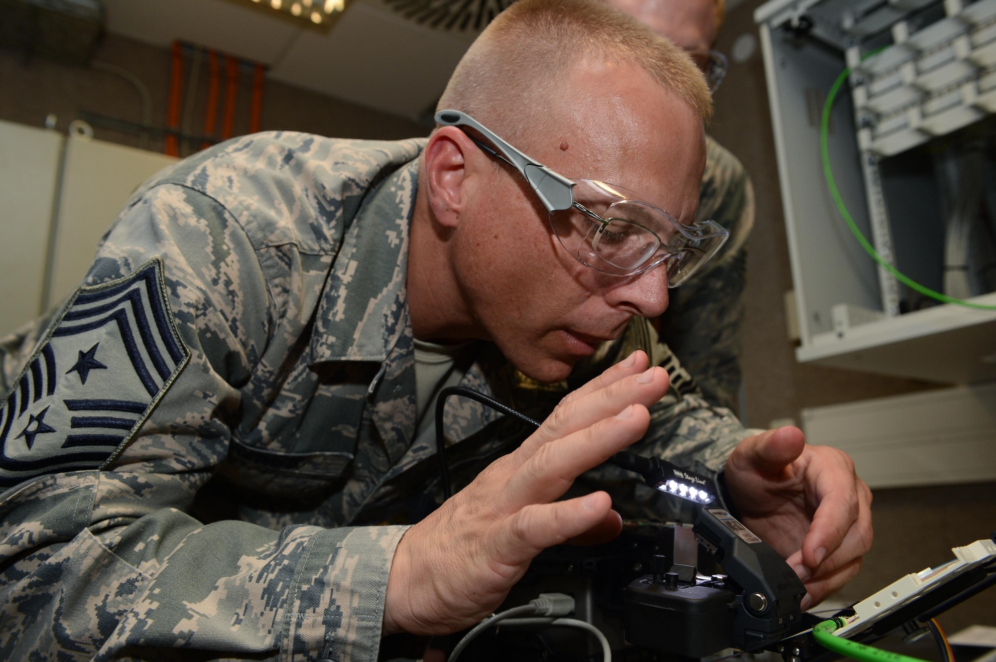 SPANGDAHLEM AIR BASE, Germany – U.S. Air Force Chief Master Sgt. Matthew Grengs, 52nd Fighter Wing command chief master sergeant, cuts a strand of fiber optic cable Aug. 14, 2013. A single strand of fiber optic cable can replace a 36 hundred pair cable, which is a copper based wire used for connecting communication networks. (U.S. Air Force photo by Airman 1st Class Kyle Gese/Released)