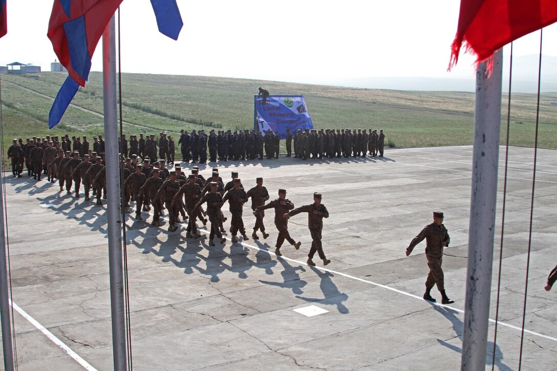 Mongolian Armed Forces service members, Mongolian General Police and U.S. Marines with Law Enforcement Battalion, 3rd Marine Expeditionary Force Headquarters Group, III Marine Expeditionary Force, march during the pass and review portion of the opening ceremony of Non-Lethal Weapons Executive Seminar (Knoles) in Five Hills Training Area, Mongolia, August 17, 2013. Knoles is a regularly scheduled field training exercise and leadership seminar sponsored annually by U.S. Marine Corp Forces Pacific, and it is designed to promote awareness and effective use of non-lethal weapons as a tool to maintain order in low-intensity or civil unrest situations.(U.S. Marine Corps Photo by Sgt John M. Ewald/released)
