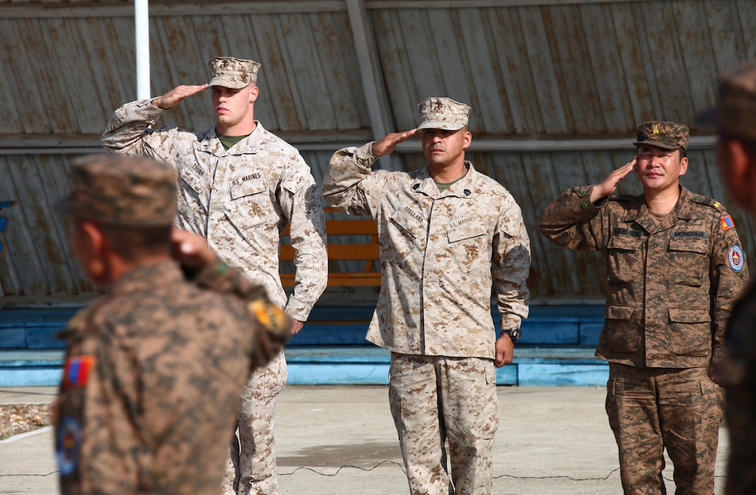 1st Lt. Ryan Trunk and Gunnery Sgt. Alexander Orellana render a salute alongside Lt. Col. D. Javklanbayar, senior staff officer for the Peace Support Operations Department, General Staff, Mongolian Armed Forces, during the opening ceremony for the Non-Lethal Weapons Executive Seminar (NOLES) 2013 at Five Hills Training Area, Mongolia, Aug. 17. NOLES is a regularly scheduled field training exercise and leadership seminar sponsored by U.S. Marine Corps Forces Pacific, and hosted annually by various nations throughout Asia-Pacific. In its 12th iteration, this multinational training event is designed to promote awareness and effective use of non-lethal weapons as a tool to maintain order in low-intensity conflict situations or during incidents of civil unrest. Mongolia, a regular participant, is hosting NOLES for the third time. Trunk, training officer with Law Enforcement Battalion, 3rd Marine Expeditionary Force Headquarters Group and officer-in-charge of the Marine detachment during the exercise is from Brookline, Mass. Orellana, company gunnery sergeant with Company B, LE Battalion, is from New York.