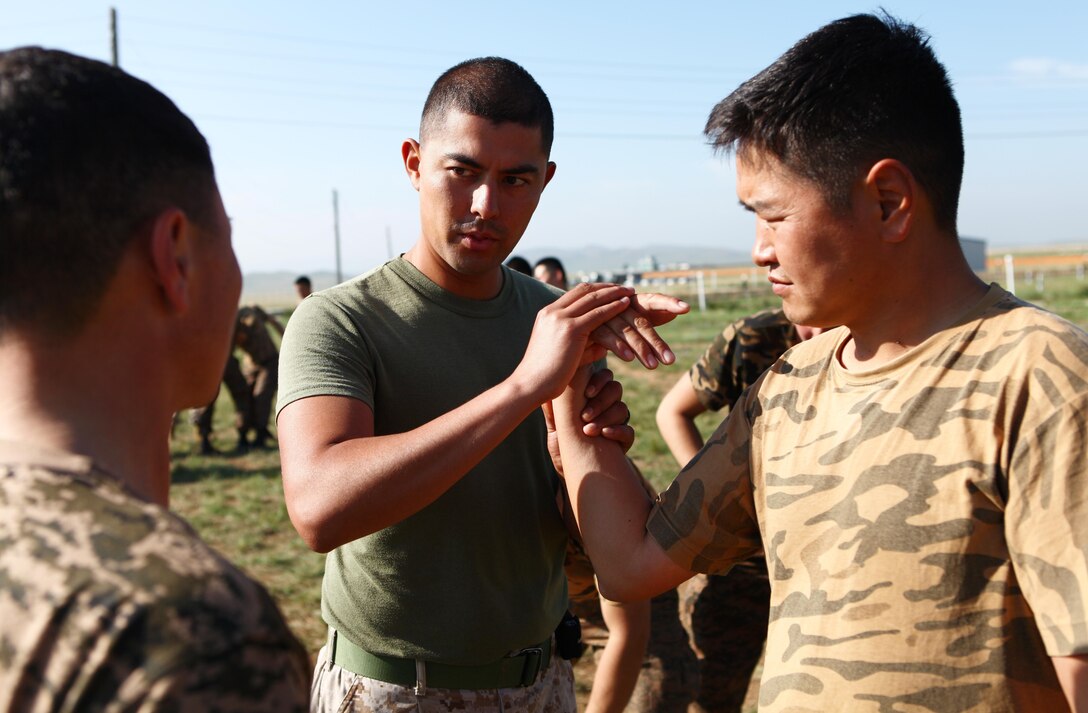 Lance Cpl. Edgar Ramirez, an assistant instructor and military policeman with Law Enforcement Battalion, 3rd Marine Expeditionary Force Headquarters Group, III MEF, demonstrates proper technique to Mongolian Armed Forces service members during Mechanical Advantage Control Hold (MACH) training, Aug. 18. Mongolian troops and police personnel are rehearsing MACHs to further develop non-lethal control techniques for use during low-intensity conflict situations. The training is taking place as part of Non-Lethal Weapons Executive Seminar (NOLES) 2013, a regularly scheduled field training exercise and leadership seminar sponsored by U.S. Marine Corps Forces Pacific, and hosted annually by various nations throughout Asia-Pacific. In its 12th iteration, this multinational training event is designed to promote awareness and effective use of non-lethal weapons. Mongolia, a regular participant, is hosting NOLES for the third time. Ramirez is from Orange, Calif.