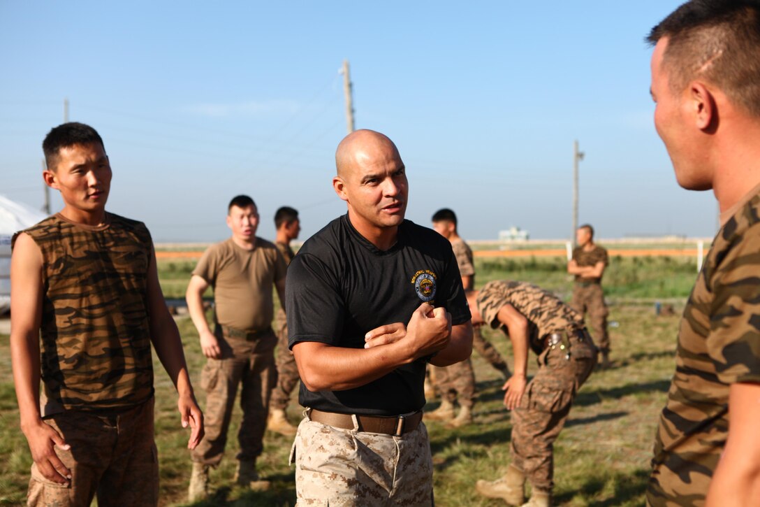 Gunnery Sgt. Alexander Orellana, chief non-lethal weapons instructor with Law Enforcement Battalion, 3rd Marine Expeditionary Force Headquarters Group, III MEF, demonstrates Mechanical Advantage Control Hold (MACH) techniques, Aug. 18. Mongolian troops and police personnel are rehearsing MACHs to further develop non-lethal control techniques for use during low-intensity conflict situations. The training is taking place as part of Non-Lethal Weapons Executive Seminar (NOLES) 2013, a regularly scheduled field training exercise and leadership seminar sponsored by U.S. Marine Corps Forces Pacific, and hosted annually by various nations throughout Asia-Pacific. In its 12th iteration, this multinational training event is designed to promote awareness and effective use of non-lethal weapons. Mongolia, a regular participant, is hosting NOLES for the third time. Orellana, from New York, is also the company gunnery sergeant for Company B, LE Battalion.