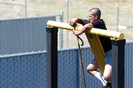 A candidate in the California National Guard's Grizzly Youth Program gets above ground to tie a rope knot July 20, 2011, during an obstacle challenge at Camp San Luis Obispo, Calif.