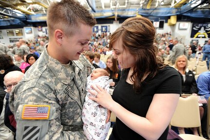 Staff Sgt. Carl Lere, South Dakota National Guard, holds his five-day-old daughter, Summer, as his wife, Sara, looks on at the activation ceremony for South Dakota Army National Guard's 196th Maneuver Enhancement Brigade May 8, 2010, at the Elmen Center, Augustana College campus in Sioux Falls.