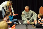 Jessica Clark-Woinarowicz, North Dakota National Guard state youth coordinator, holds the microphone for Guard children to ask Army Maj. Gen. David Sprynczynatyk, North Dakota adjutant general, some impromptu questions at the Adjutant General's Symposium for Families in Bismarck, N.D., March 5.