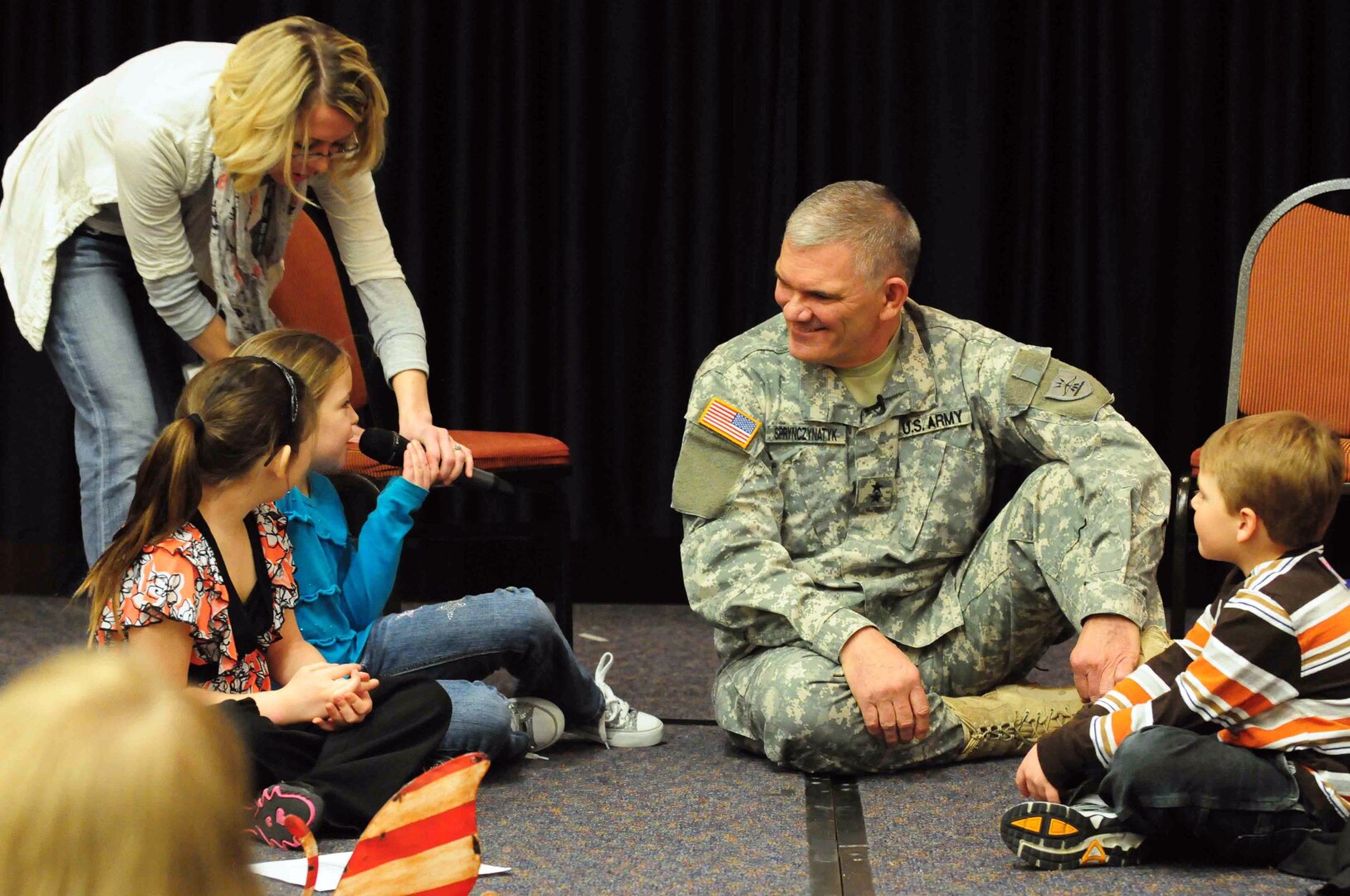 Jessica Clark-Woinarowicz, North Dakota National Guard state youth coordinator, holds the microphone for Guard children to ask Army Maj. Gen. David Sprynczynatyk, North Dakota adjutant general, some impromptu questions at the Adjutant General's Symposium for Families in Bismarck, N.D., March 5.