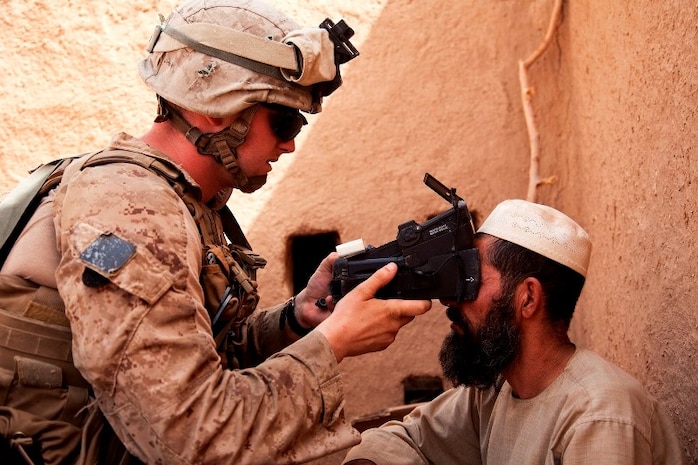 Lance Cpl. Andrew Derr, Fox Company, 2nd Battalion, 2nd Marine Regiment, scans an Afghan man's retinas with the Biometric Enrollment and Screening Device while conducting counter-insurgency operations in Helmand province, Afghanistan, July 17.
