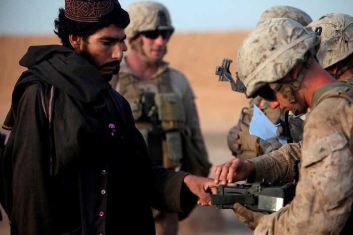 Marines with Fox Company, 2nd Battalion, 2nd Marine Regiment, fingerprints an Afghan man with the Biometric Enrollment and Screening Device while searching compounds near Patrol Base Boldak, Afghanistan, during Operation Grizzly IV July 29. 