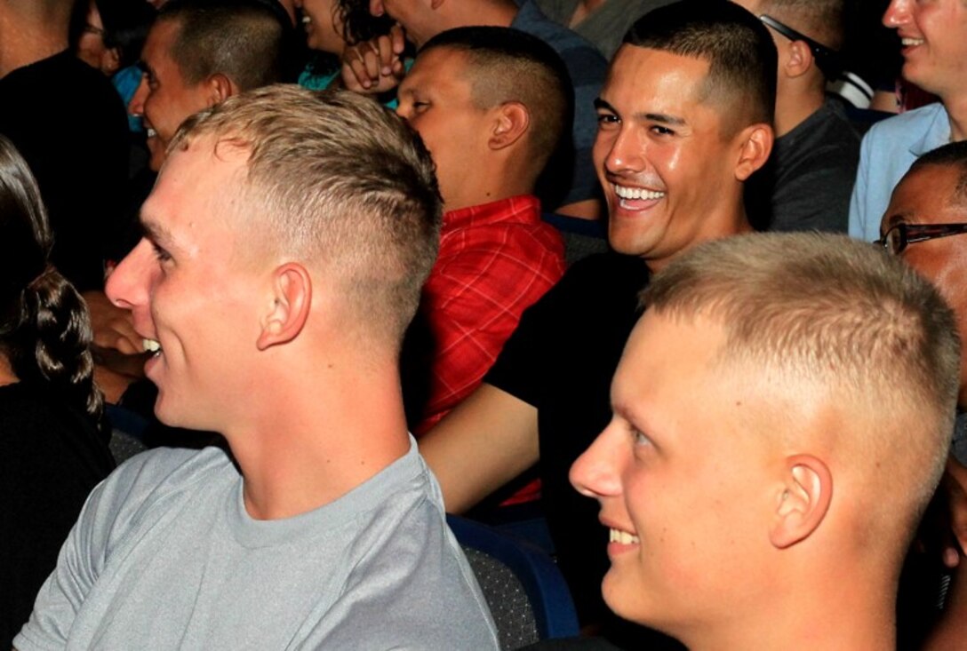 Marines and sailors laugh during a stand-up comedy performance at the base theater Aug. 9, 2013.