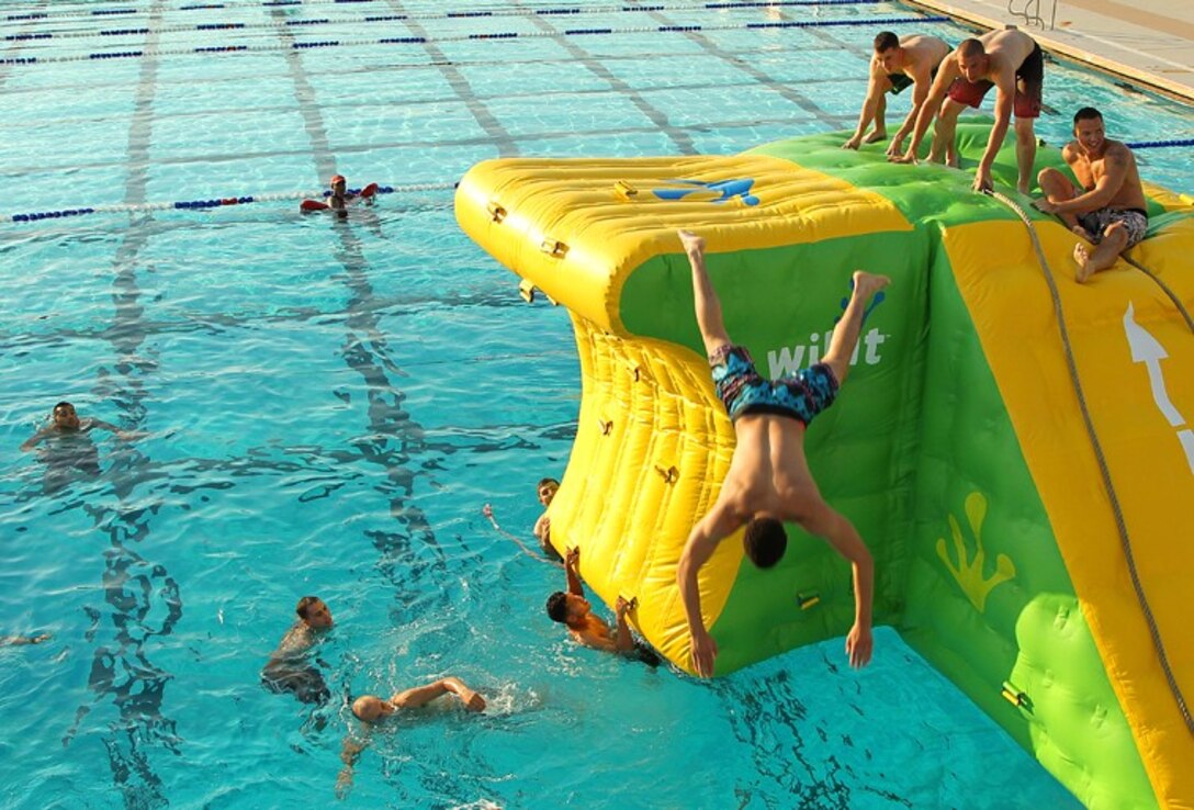 pl. Matthew Allen, combat photographer, Combat Camera Headquarters Battalion, dclimbs to the top of an inflatable structure during the battalion’s pool party at the Training Tank Aug. 8, 2013.
