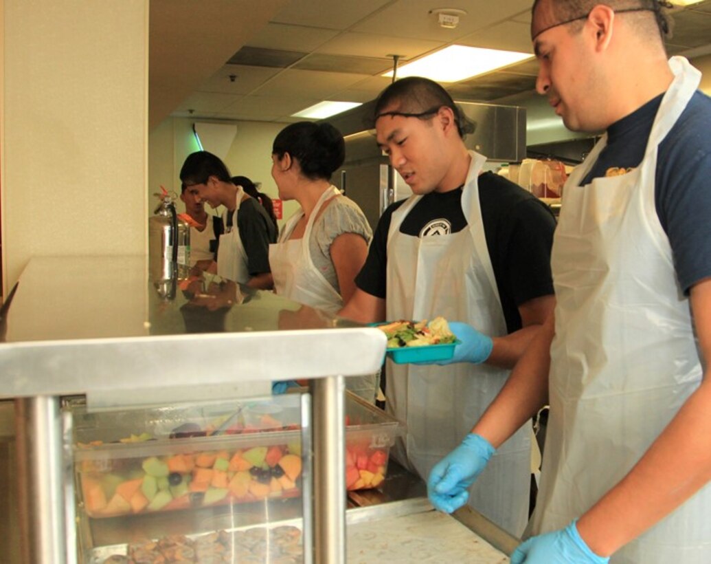 Petty Officer 2nd Class Marvin Gomez, surgical technologist, and Petty Officer 3rd Class Allen Ly, dental technician,  both with 23rd Dental Co. serve food at Martha’s Village and Kitchen, a homeless shelter in Indio, Calif., Aug. 10, 2013.
