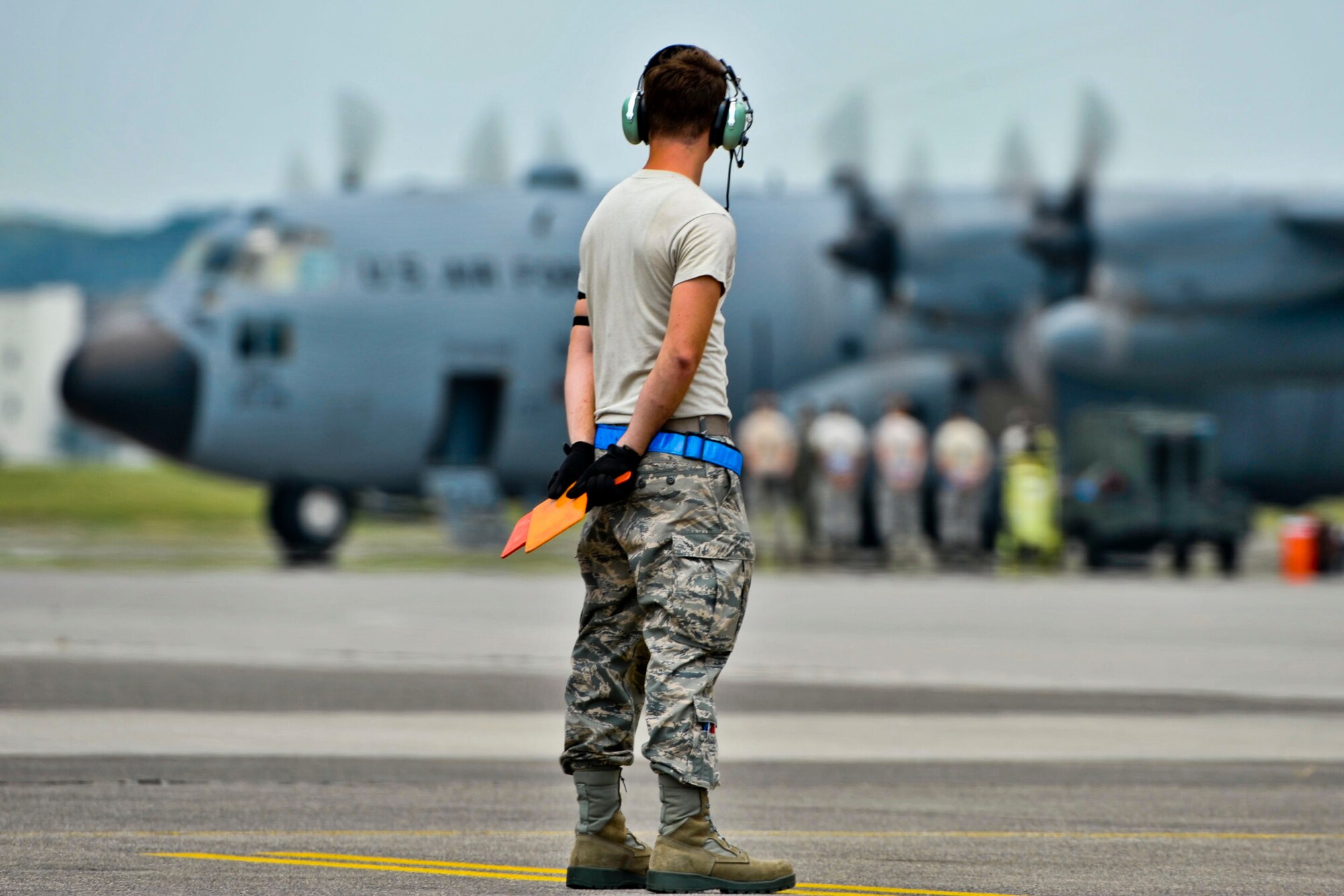YOKOTA AIR BASE, Japan – An Airman stands by as a C-130 Hercules prepares to taxi across the flightline at Yokota Air Base, Japan, Aug. 19, 2013, during a large formation mission.  The mission allowed the 374th to practice and display its role as the primary Western Pacific airlift hub.  (U.S. Air Force photo by Airman 1st Class Soo C. Kim)