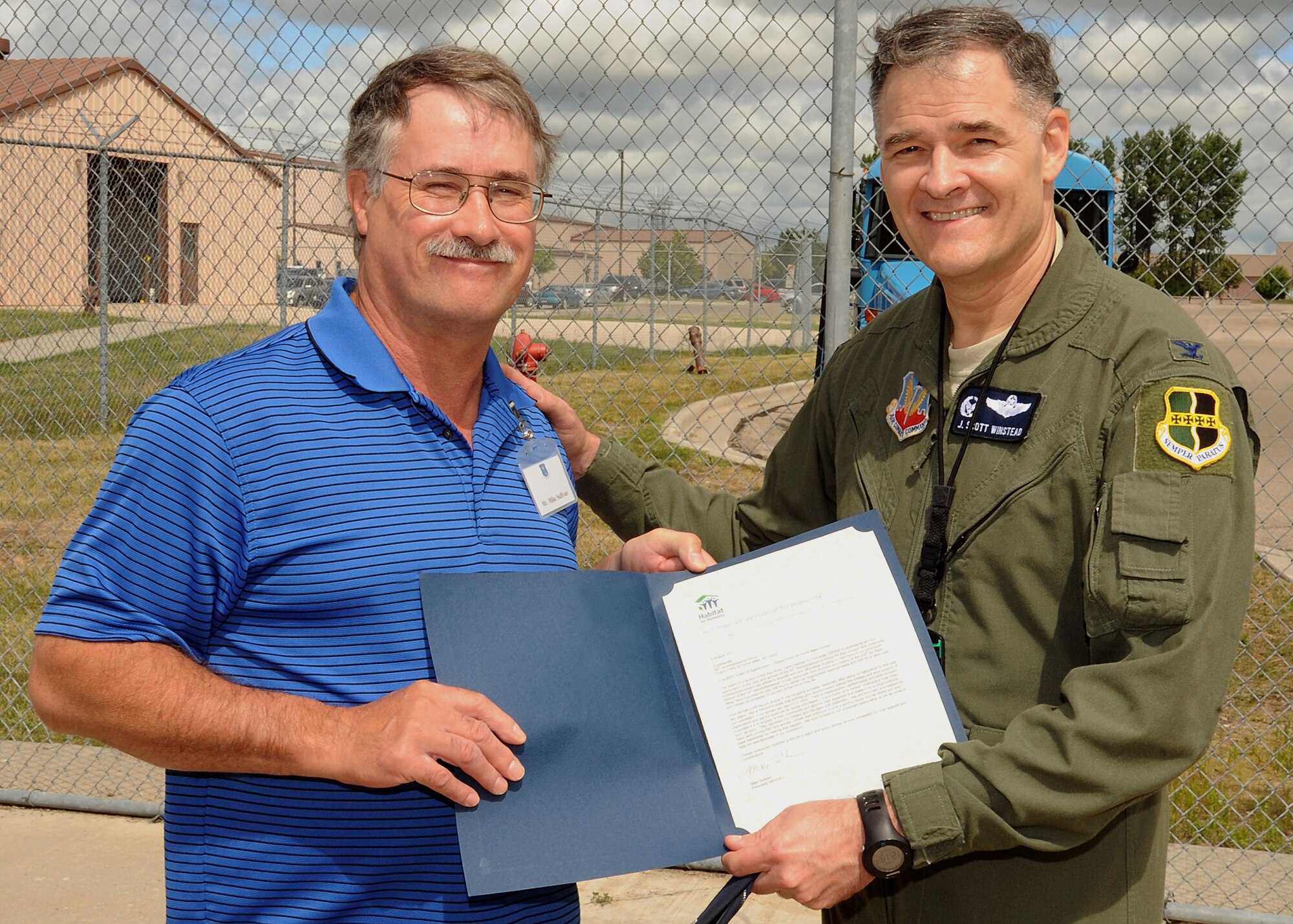 Mike Sullivan, president of Habitat for Humanity, presents Col. J. Scott Winstead, 69th Reconnaissance Group commander, with a letter of appreciation for the work base volunteers have given to  community housing projects in the city of Grand Forks, N.D. Since 1987, Habitat for Humanity has rehabilitated 22 homes in Grand Forks and one home in East Grand Forks, Minn. (U.S. Air Force photo/Airman 1st Class Zachiah Roberson)