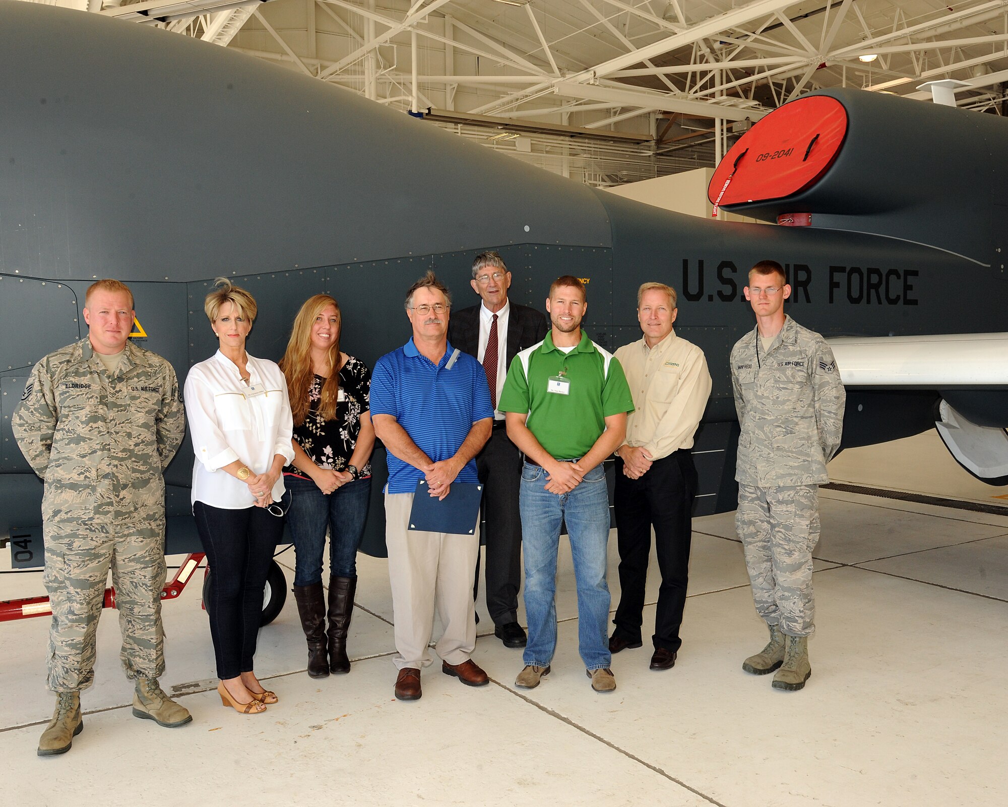 Members of the Habitat for Humanity board stand next to a RQ-4 Block 40 Global Hawk with Staff Sgt. Patrick Eldridge, 319th Contracting Flight contract specialist, and 69th Maintenance Squadron avionics journeyman Senior Airman Christopher Manfredo, Aug. 9, 2013 on Grand Forks Air Force Base, N.D. The mission of Habitat for Humanity is to assist low income individuals own their own homes. (U.S. Air Force photo/Airman 1st Class Zachiah Roberson) 