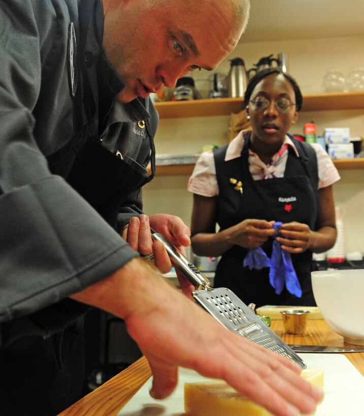 Army Staff Sgt. David Cantwell, U.S. Army Priority Air Transport flight steward, teaches Air Force Staff Sgt. Kenyeta Brackett, 1st Airlift Squadron flight attendant, different cooking techniques during a joint service culinary training session on Joint Base Andrews, Md., Aug. 14, 2013. The Soldiers and Airmen traded ideas and methods and enjoyed each other’s culinary creations afterward. (U.S. Air Force photo/Airman 1st Class Erin O’Shea) 