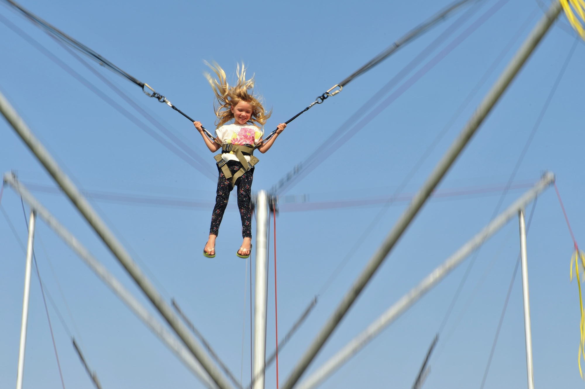 The daughter of a 460th Force Support Squadron member jumps on a bungee trampoline during Fun Fest Aug. 16, 2013, at the softball fields on Buckley Air Force Base, Colo. Fun Fest is an annual Buckley birthday celebration which includes a day full of field-day activities and a community fair. (U.S. Air Force photo by Senior Airman Phillip Houk/Released)