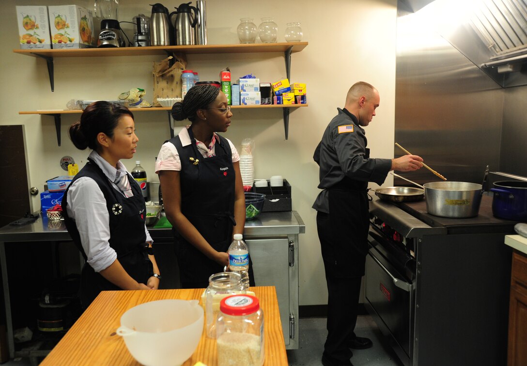 Staff Sgt. Christine Kim and Kenyeta Brackett, 1st Airlift Squadron flight attendants, observe Army Staff Sgt. David Cantwell, U.S. Army Priority Air Transport flight steward, as he prepares a rice dish during a joint service culinary training session on Joint Base Andrews, Md., Aug. 14, 2013. Army stewards and Air Force flight attendants conducted a training class to exchange knowledge and skills from one another. (U.S. Air Force photo/Airman 1st Class Erin O’Shea)