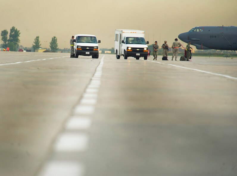 Airmen from the 5th Security Forces Squadron and Airmen from the 5th Aircraft Maintenance Squadron perform their perspective duties during a minimum-interval takeoff at Minot Air Force Base, N.D., Aug. 15, 2013. A MITO take-off uses starter cartridges filled with gun powder to quickly fire up the B-52’s engines. (U.S. Air Force photo/Senior Airman Brittany Y. Auld)