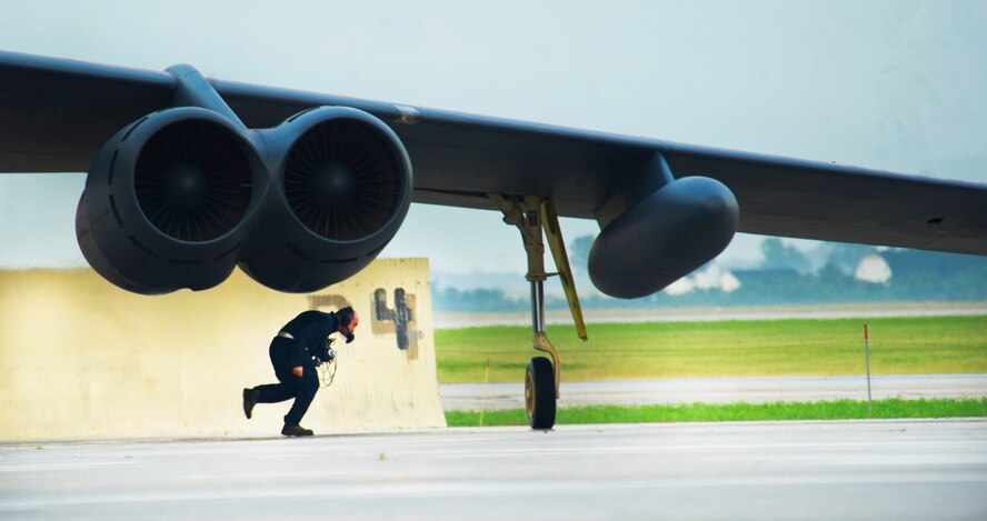 A crew chief from the 5th Aircraft Maintenance Squadron runs to get in position during a minimum-interval takeoff at Minot Air Force Base, N.D., Aug. 15, 2013. In a conventional conflict, the B-52 can perform strategic attack, close-air support, air interdiction, offensive counter-air and maritime operations. (U.S. Air Force photo/Senior Airman Brittany Y. Auld)