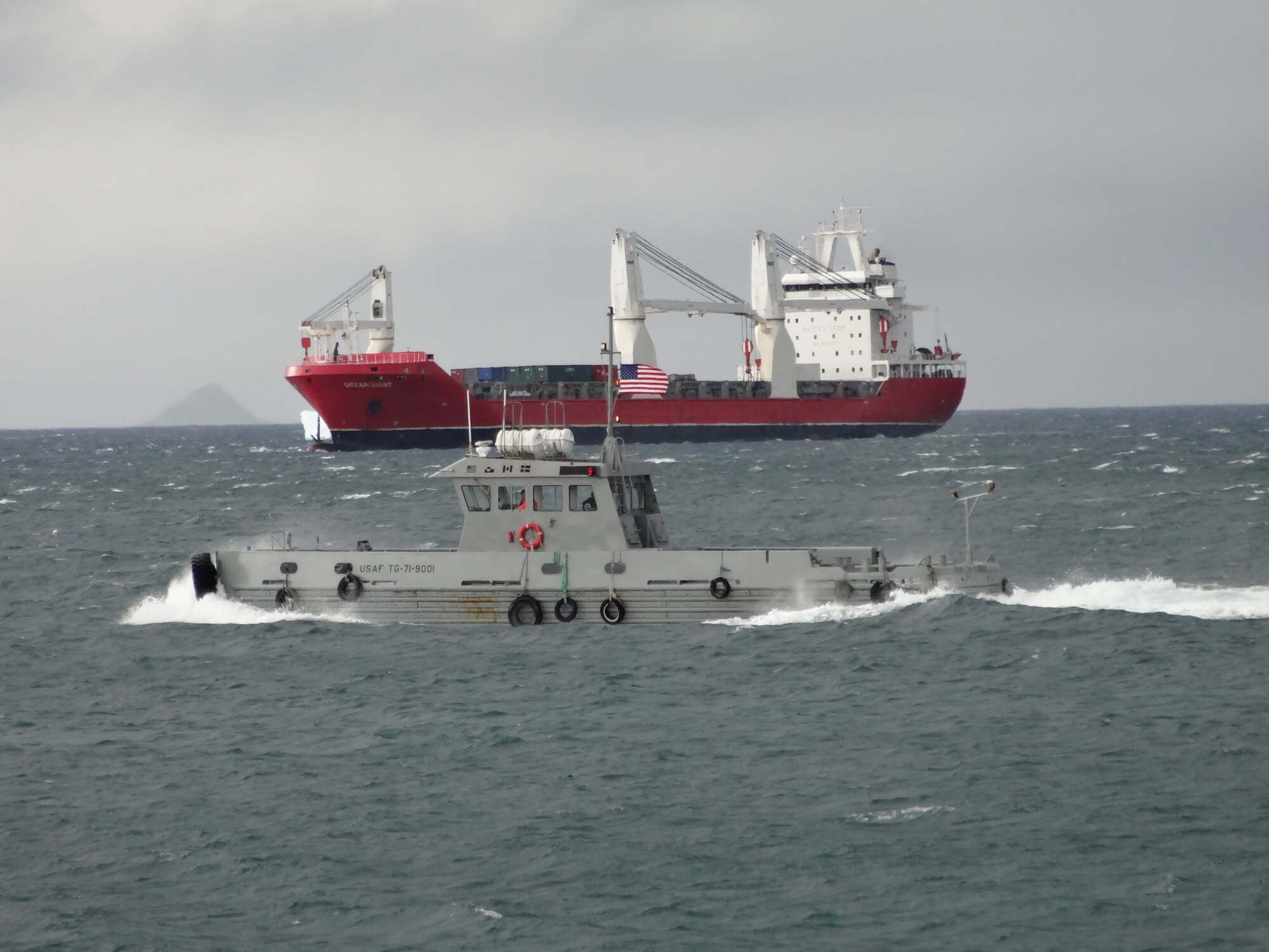 THULE AIR BASE, Greenland -- The Ocean Giant waits in the bay for tanker operations to finish, while the Rising Star, the Air Force’s only pusher boat, motors through the bay. The Rising Star helped position cargo ships into and out of Thule’s port during Operation Pacer Goose, Thule’s annual resupply mission. Thule is located 750 miles north of the Arctic Circle and is home to the northernmost deep water port in the world. Both the CPO Germany and Ocean Giant had to be escorted through the ice by a Canadian Coast Guard ice breaker. (U.S. Air Force photo/Master Sgt. Levi Wells)