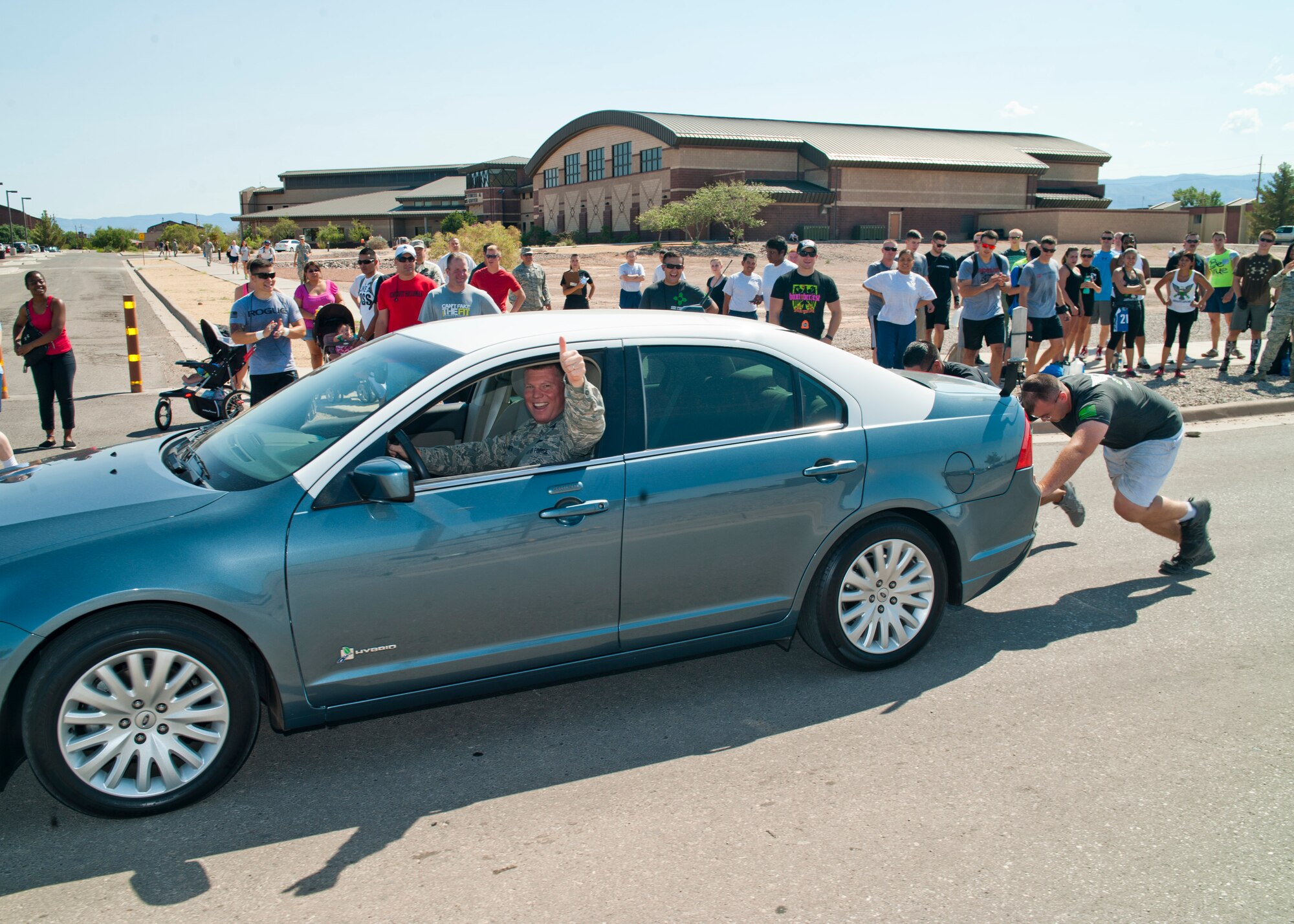 Two Airmen push a car containing Col. Andrew Croft, 49th Wing commander, as a part of the “Fittest Wingman Challenge” at Holloman Air Force Base, N.M., Aug. 16. The Fittest Wingman Challenge was part of Comprehensive Airman Fitness Day which encouraged a total fitness approach to well-being. This quarters CAF day was focused on physical fitness, members of Team Holloman participated in a wing run, followed by various sporting events.  Participants learned the importance of physical activity and comradery. (U.S. Air Force photo by Airman 1st Class Daniel E. Liddicoet/Released)
