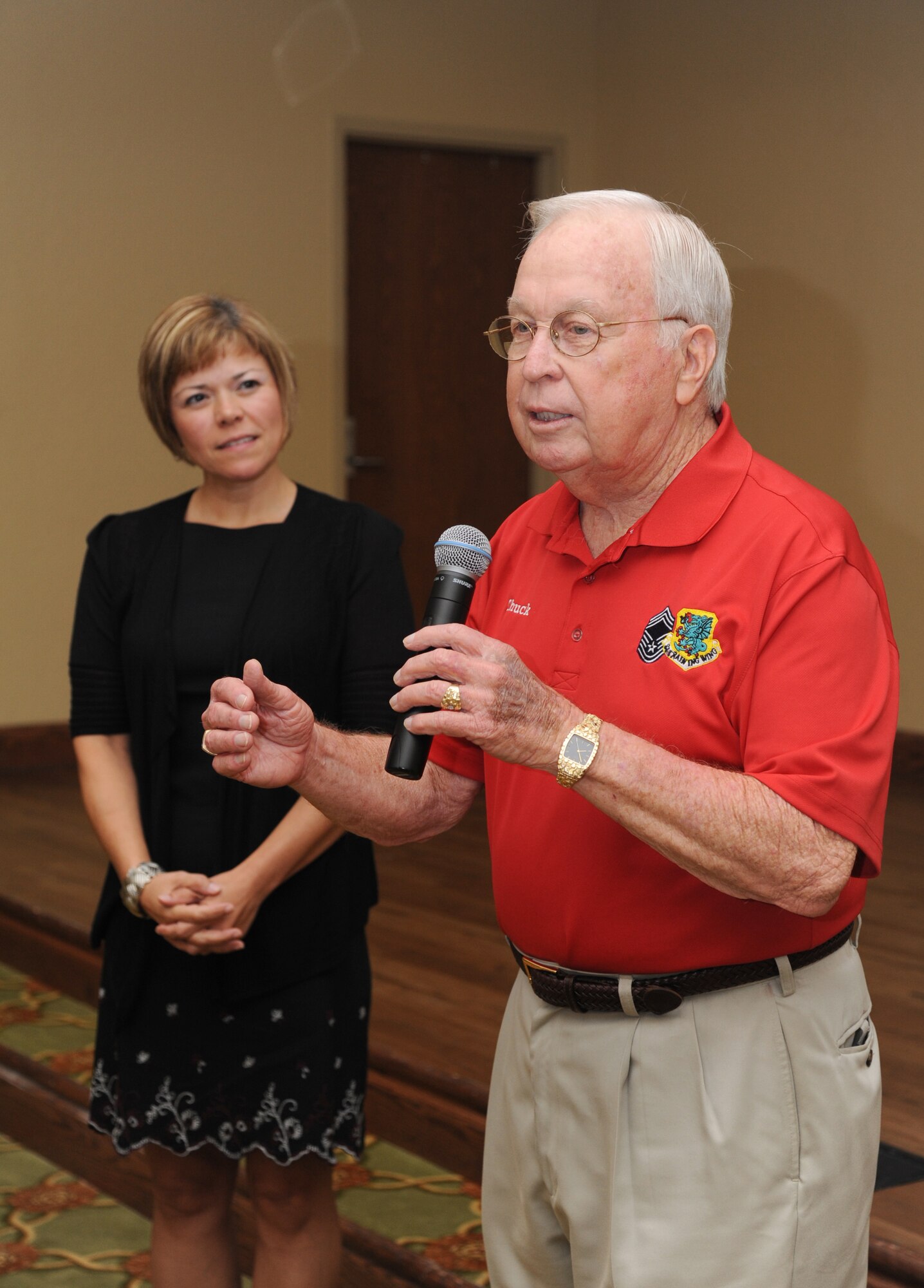 Chief Master Sgt. Angie Johnson, 81st Training Wing command chief, stands by as retired Chief Master Sgt. Chuck Teston, provides remarks during the Johnson’s farewell dinner Aug. 15, 2013, at the Bay Breeze Event Center, Keesler Air Force Base, Miss. Johnson leaves Keesler to become the command chief for Air Force Space Command’s Space and Missile Systems Center, Los Angeles Air Force Base, Calif.  (U.S. Air Force photo by Kemberly Groue)