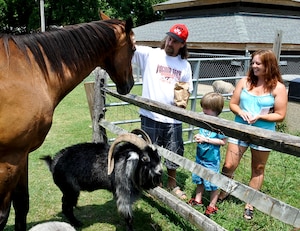 Deniel Cannon and his wife, Samantha, pet animals with their son, Lincoln, at Blue Bird Gap Farm in Hampton,Va., August 2, 2013. Blue Bird Gap Farm is designed to resemble a working farm and features farm animals and fowl of all types, as well as wild animals native to Virginia. (U.S. Air Force photo by Staff Sgt. Wesley Farnsworth/Released)