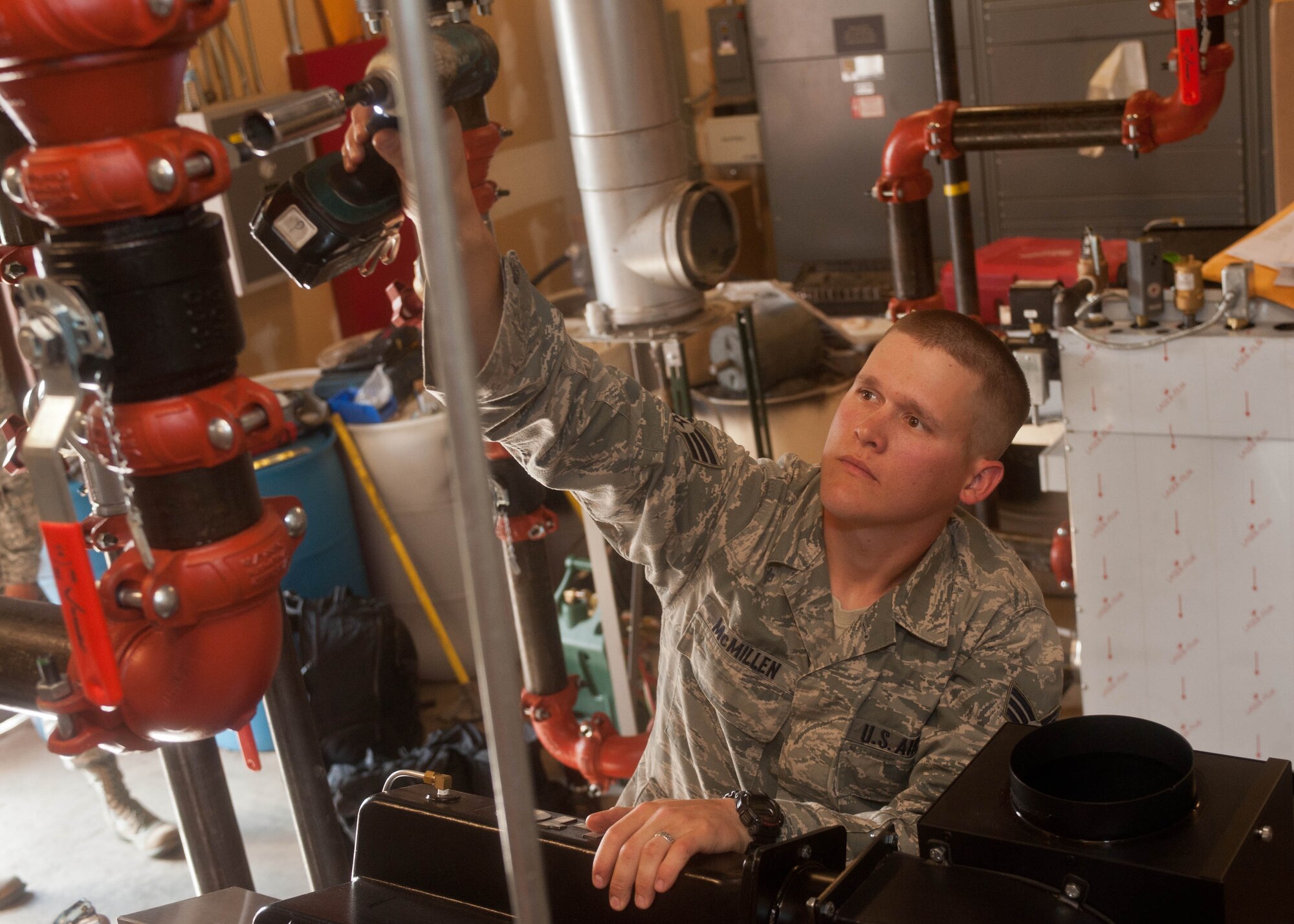 Senior Airman David McMillen, 28th Civil Engineer Squadron heating, ventilation and air conditioning technician, secures water pipes during the installation of a new boiler system in the base Exchange at Ellsworth Air Force Base, S.D., Aug. 15, 2013. The old heating and cooling equipment was replaced with an upgraded environmentally friendly boiler system, which is cost effective and conserves energy. (U.S. Air Force photo by Airman 1st Class Zachary Hada/Released)
