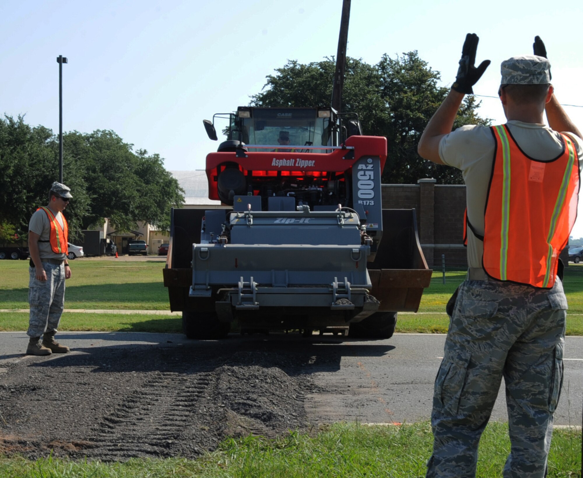 Airman 1st Class Cameron Kruell, 2nd Civil Engineer Squadron pavement and equipment section, guides an asphalt zipper into place during road construction on Barksdale Air Force Base, La., Aug. 19, 2013. The zipper is used to compact and smooth out gravel and is one of the many tools CE Airmen use during their day-to-day operations. (U.S. Air Force photo/Senior Airman Sean Martin)