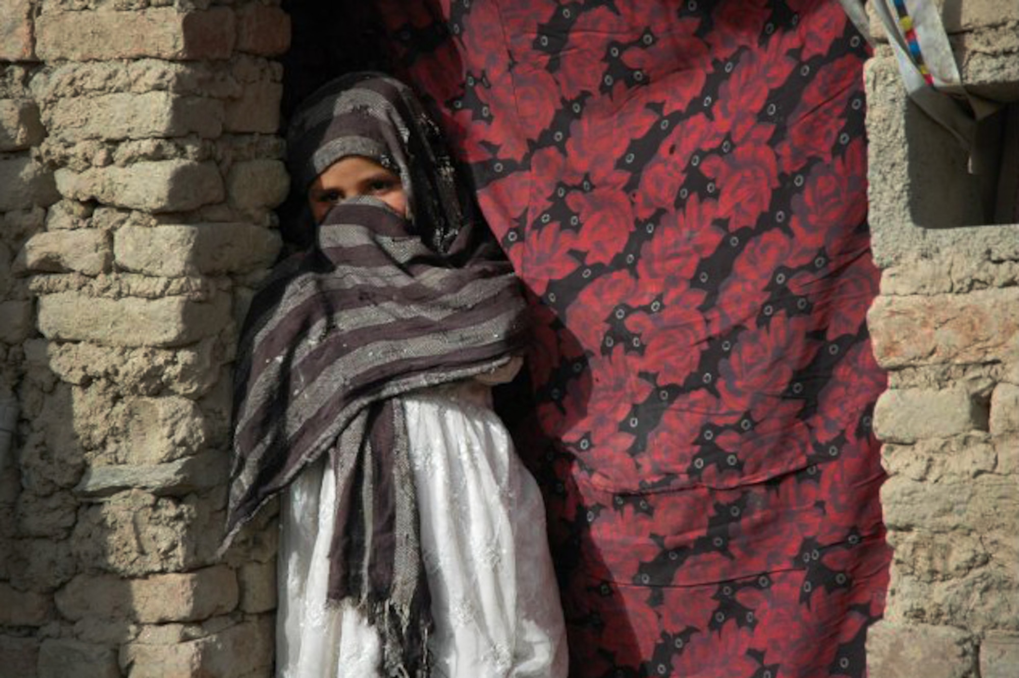 A child stands in the doorway of her families dried mud hut as living conditions in the remote villages of Afghanistan are primitive. Retired Lt. Gen. John Bradley and wife Jan, founders of the Lamia Afghan Foundation, have collected and delivered more than two million pounds of aid for  Afghanistan Mid-January 2010. In all, the Bradleys are working on building the seventh school and have collected and delivered more than two million pounds of supplies. (Courtesy photo)