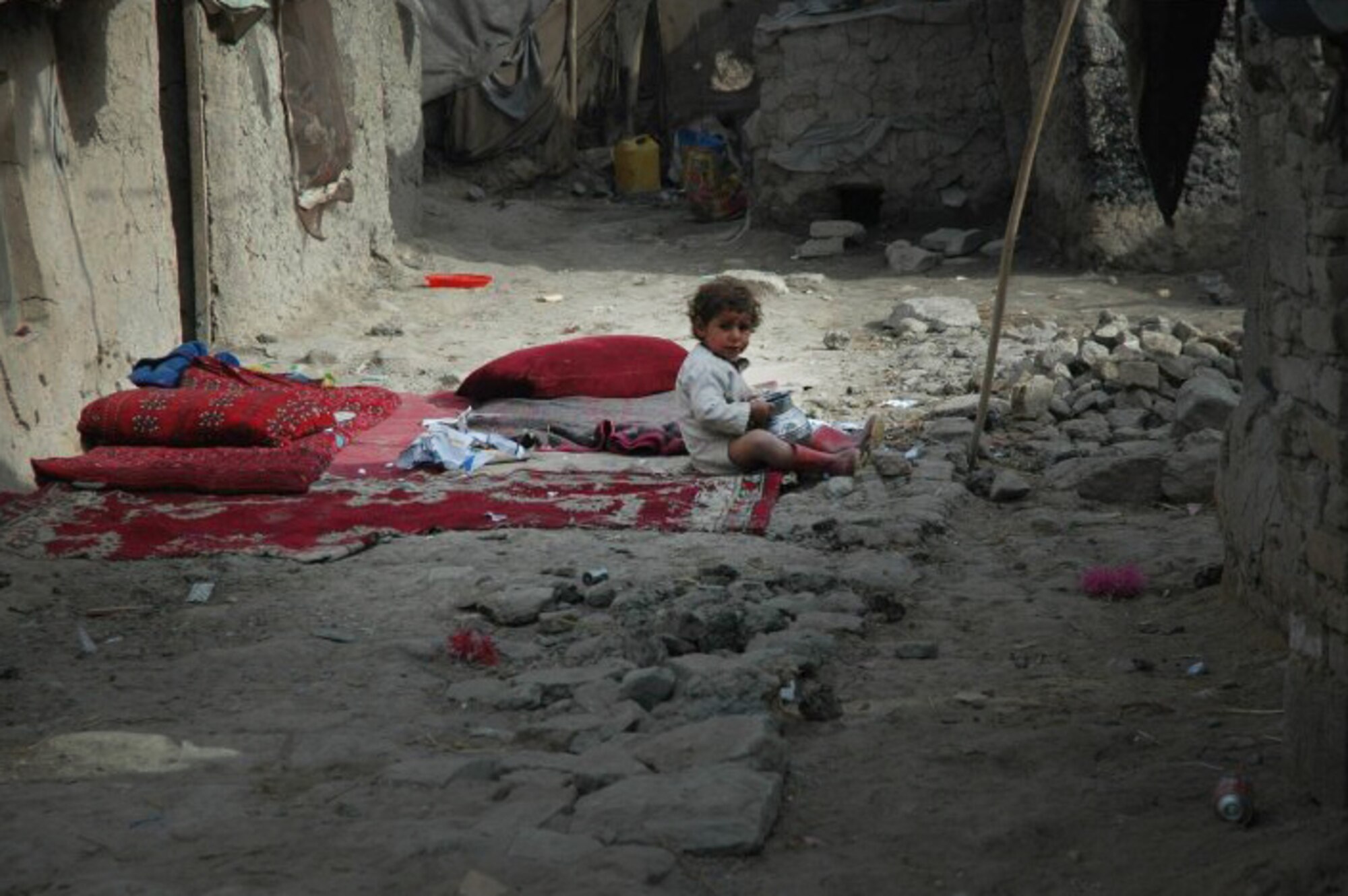 A child sits at the edge of his families bedding in an open air alleyway as living conditions in the remote villages of Afghanistan are primitive. Retired Lt. Gen. John Bradley and wife Jan, founders of the Lamia Afghan Foundation, have collected and delivered more than two million pounds of aid for  Afghanistan Mid-January 2010. In all, the Bradleys are working on building the seventh school and have collected and delivered more than two million pounds of supplies. (Courtesy photo)