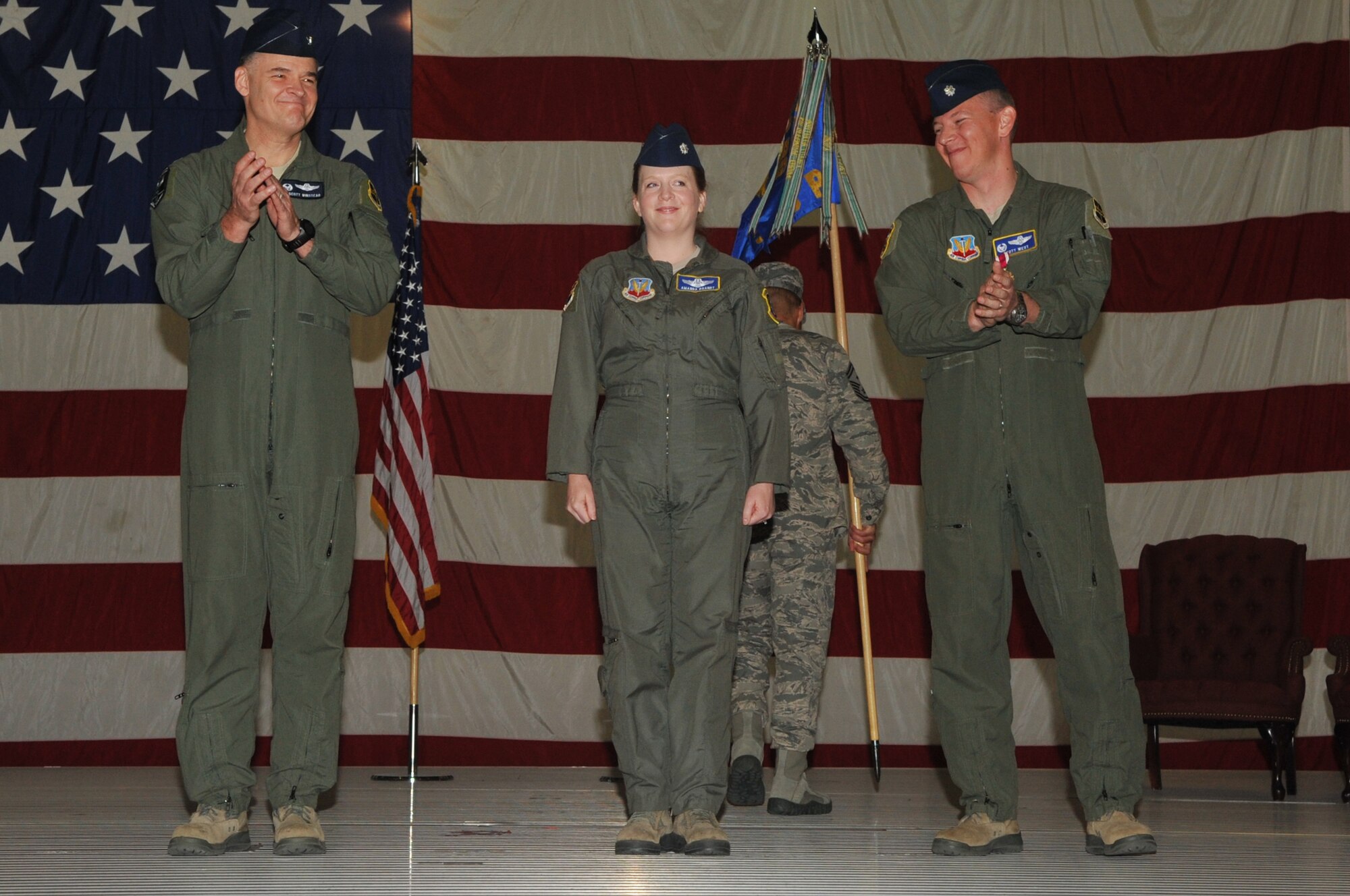 Col. J. Scott Winstead, 69th Reconnaissance Group commander (left), and Lt. Col. Scott West, former 348th Reconnaissance Squadron commander (right), applaud Lt. Col. Amanda Brant, 348th RS commander, during the 348th RS change of command ceremony Aug. 9, 2013, on Grand Forks Air Force Base, N.D. (U.S. Air Force photo/ Staff Sgt. Amanda N. Grabiec)