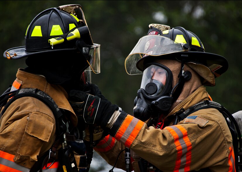 Timothy Panzer helps Senior Airman Paul Steele, of the 96th Civil Engineer Squadron; secure his gas mask before entering the area of a simulated explosion during a radiological and force protection condition exercise Aug. 16 at Eglin Air Force Base, Fla.  First responders from security forces, the fire department and medical group arrived to secure the scene and help the simulated victims.  (U.S. Air Force photo/Samuel King Jr.)