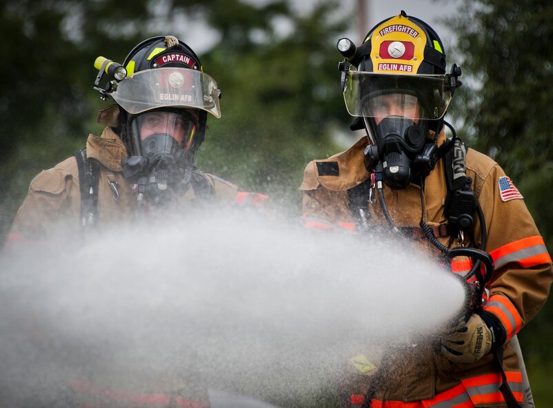 Timothy Panzer helps Senior Airman Paul Steele, of the 96th Civil Engineer Squadron, spray down a fire caused by a simulated explosion during a radiological and force protection condition exercise Aug. 16 at Eglin Air Force Base, Fla.  First responders from security forces, the fire department and medical group arrived to secure the scene and help the simulated victims.  (U.S. Air Force photo/Samuel King Jr.)