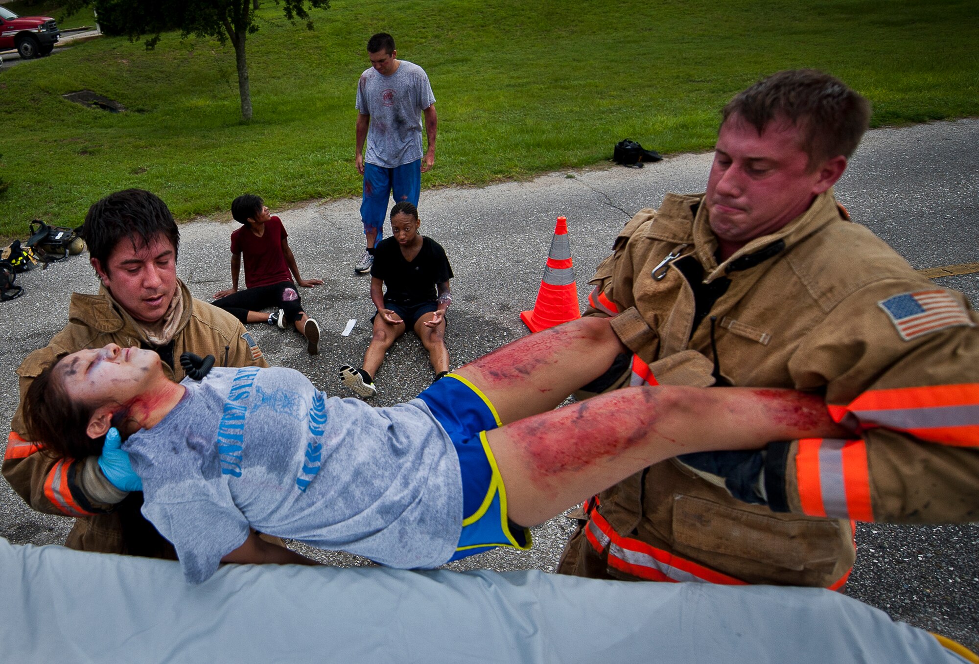 Firefighters from the 96th Civil Engineer Squadron lift an unconscious patient onto a gurney for transport to the hospital after a simulated explosion during a radiological and force protection condition exercise Aug. 16 at Eglin Air Force Base, Fla.  First responders from security forces, the fire department and medical group arrived to secure the scene and help the simulated victims.  (U.S. Air Force photo/Samuel King Jr.)