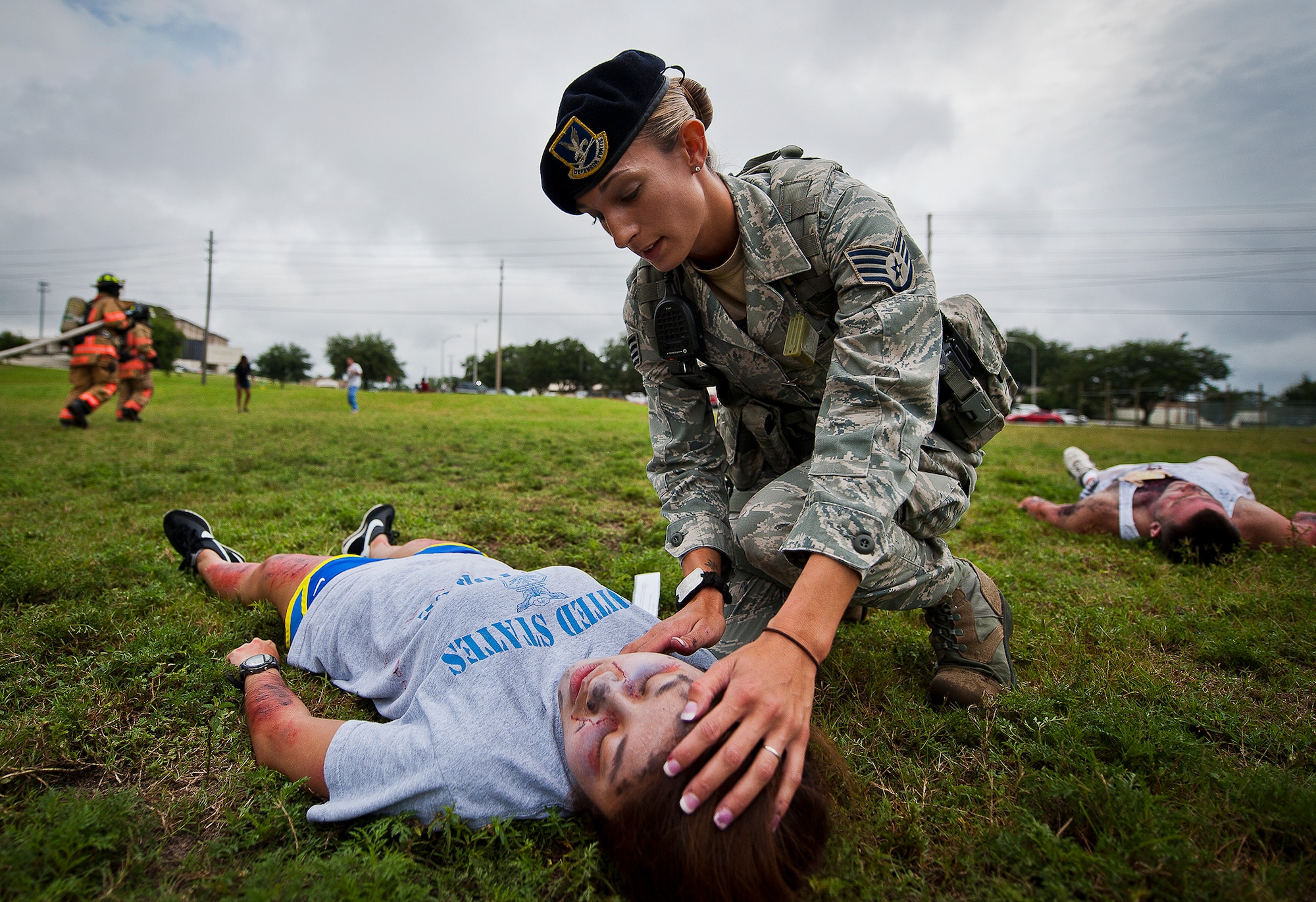 Staff Sgt. Jacqueline Lawson, of the 96th Security Forces Squadron, checks the pulse of an unconscious victim as firefighters move toward other injured Airmen after a simulated explosion during a radiological and force protection condition exercise Aug. 16 at Eglin Air Force Base, Fla.  First responders from security forces, the fire department and medical group arrived to secure the scene and help the simulated victims.  (U.S. Air Force photo/Samuel King Jr.)